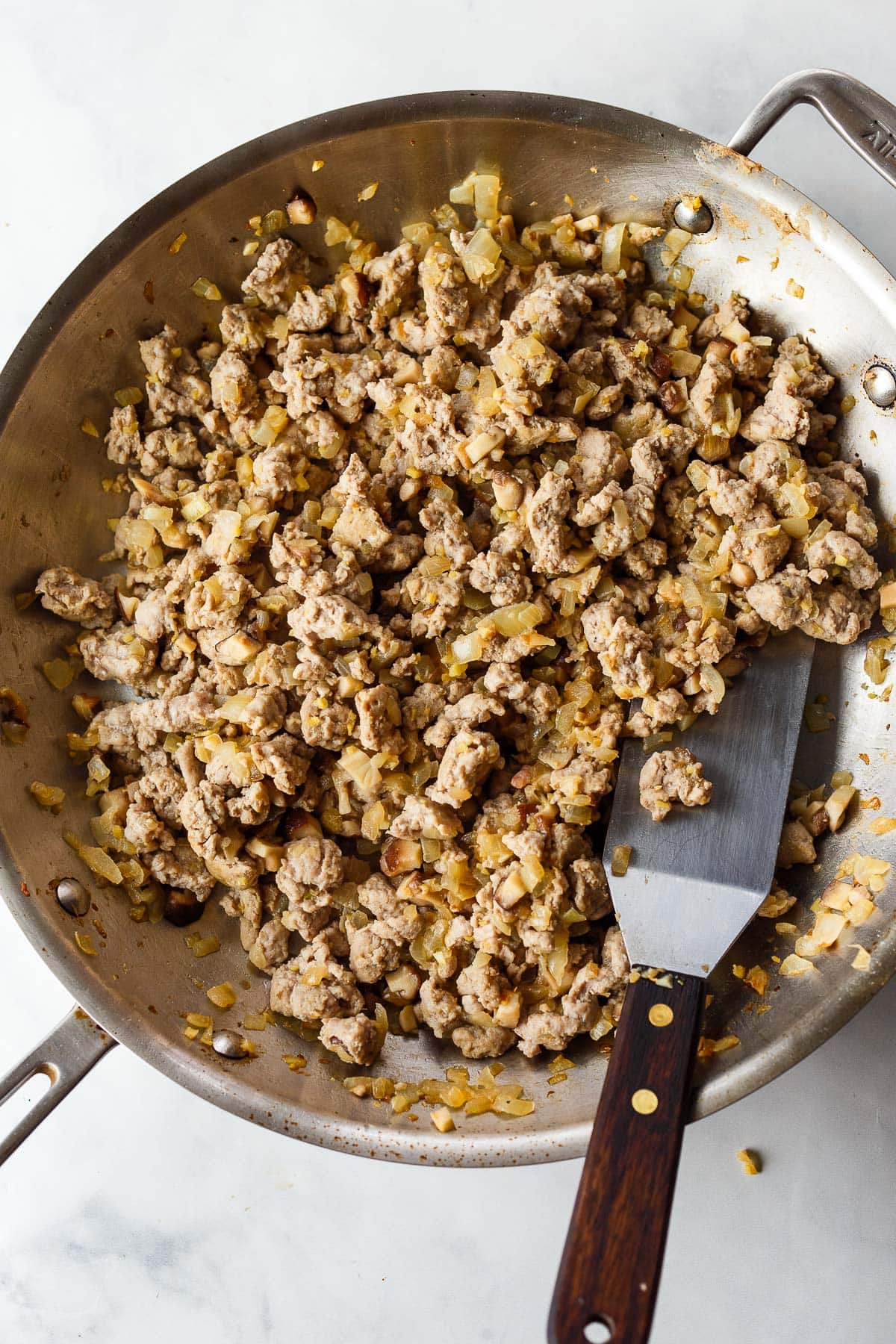 pan with ground turkey and sautéed onions with spatula, to make filling for Asian lettuce cups. 