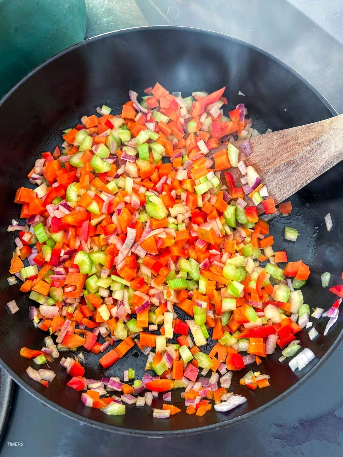 large pot with diced veggies sautéing with wooden spatula. 