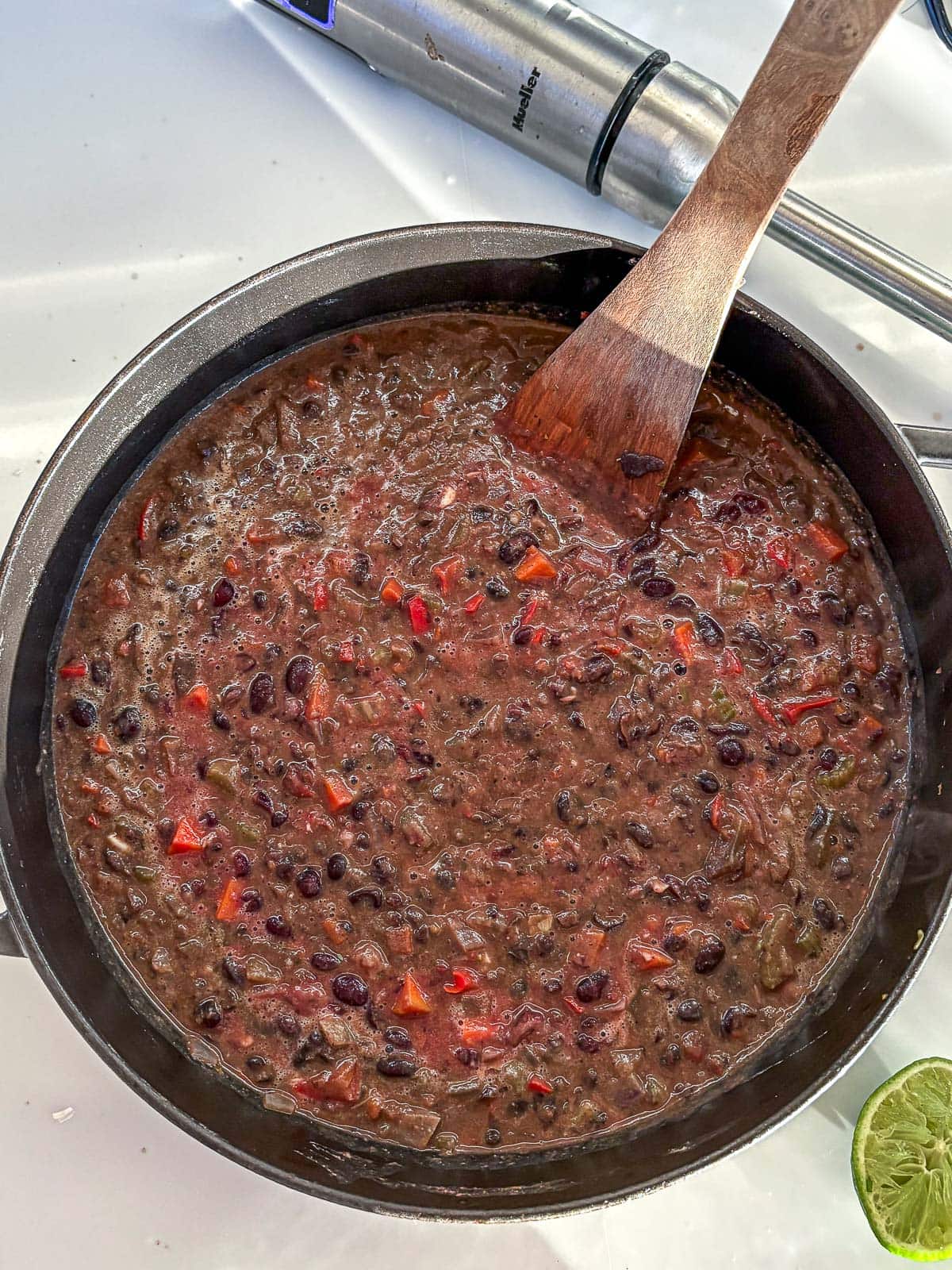 creamy black bean soup in large pot with wooden spatula. 