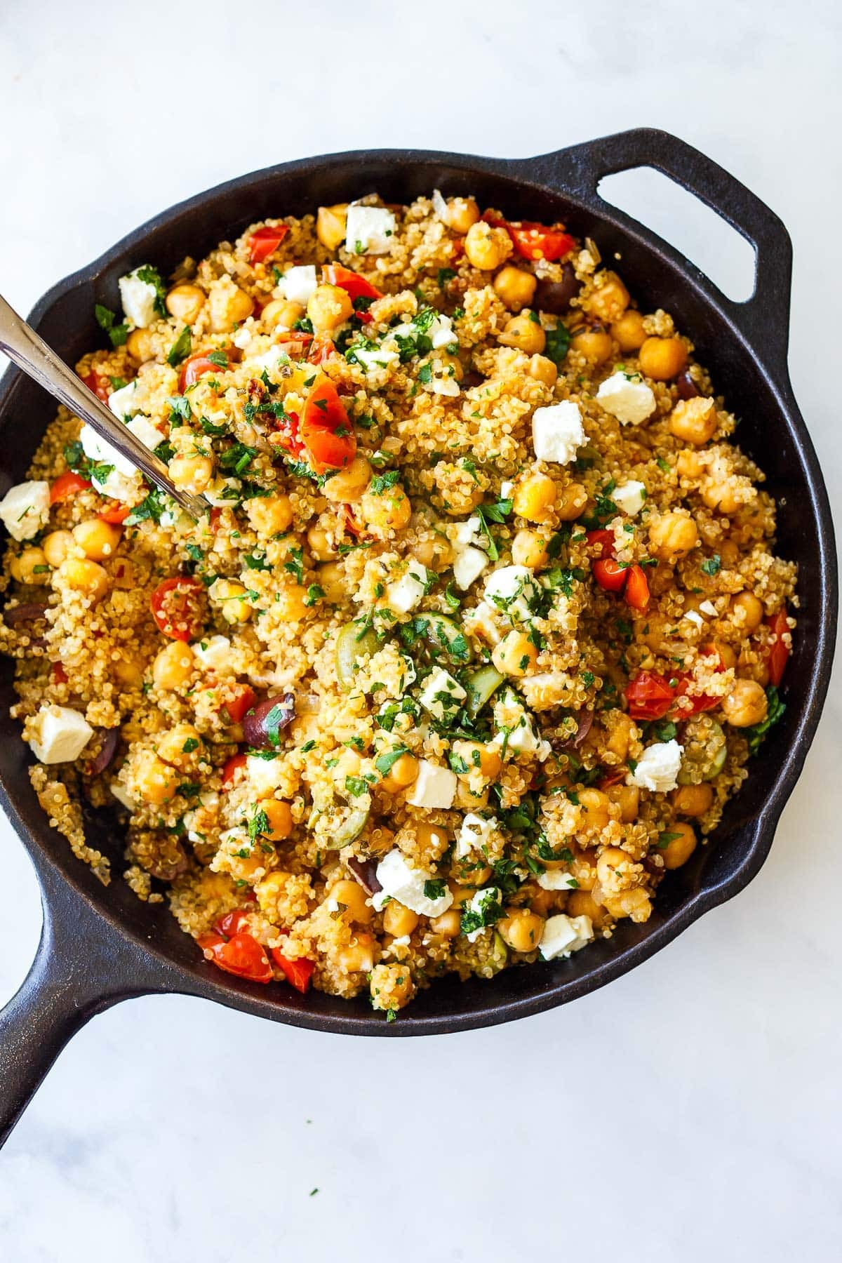 cast iron skillet with Mediterranean chickpea skillet with feta, herbs, olives, and tomatoes. 