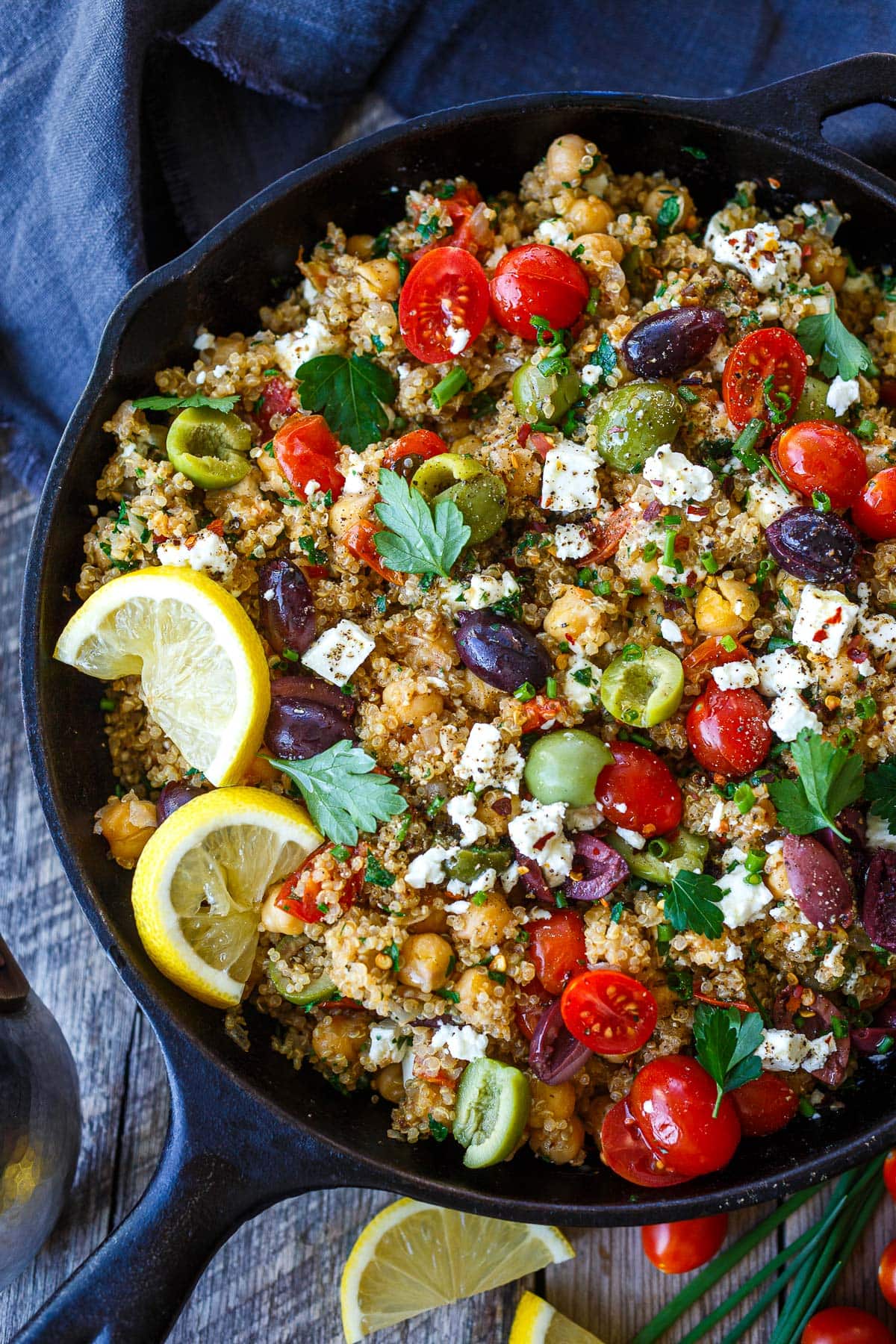Mediterranean chickpea skillet with olives, fresh herbs and chives, cherry tomatoes, crumbled feta, and lemon wedges.