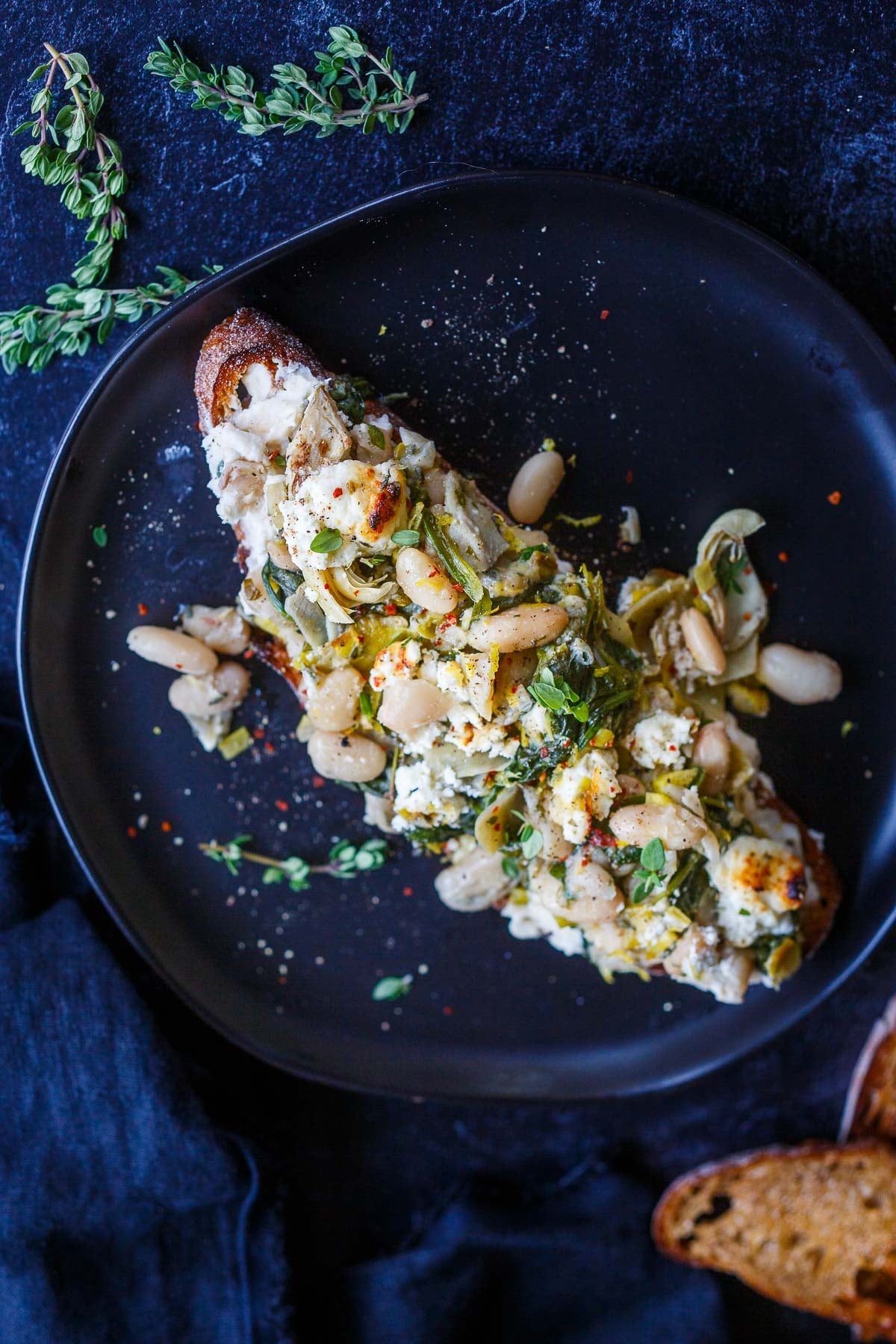 white bean artichoke skillet with broiled goat cheese, lemon wedges, and fresh herbs.