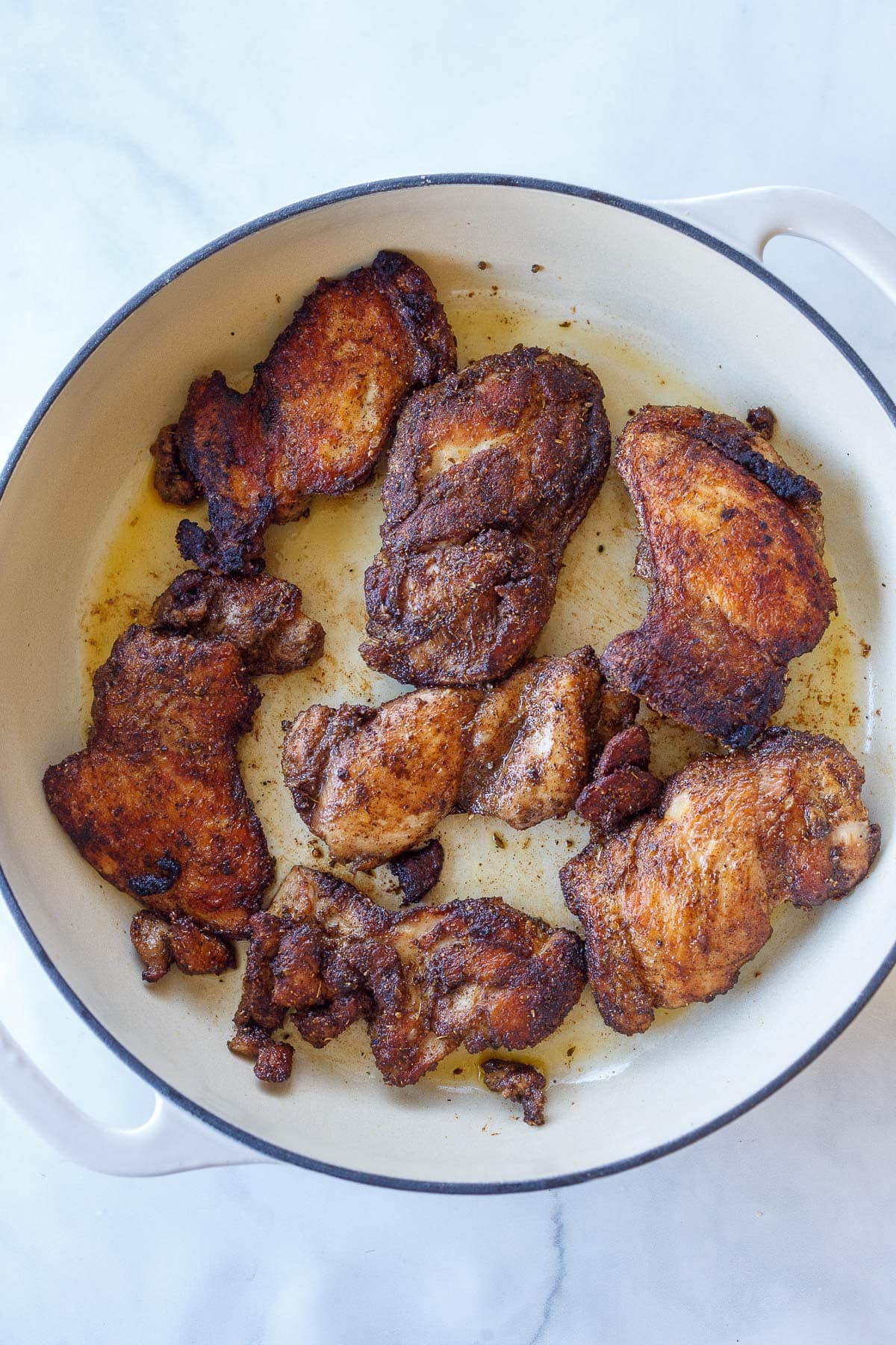 Dutch oven with seared chicken thighs with Mexican spices. 