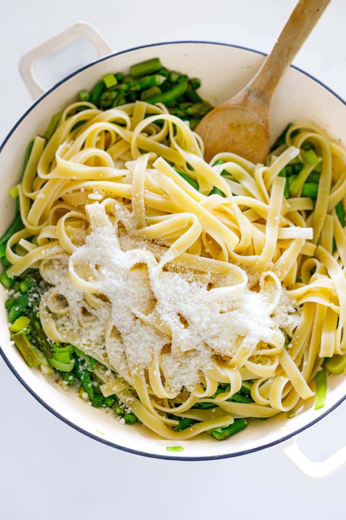 Combining the pasta with veggies cheese, pasta water and cream. 