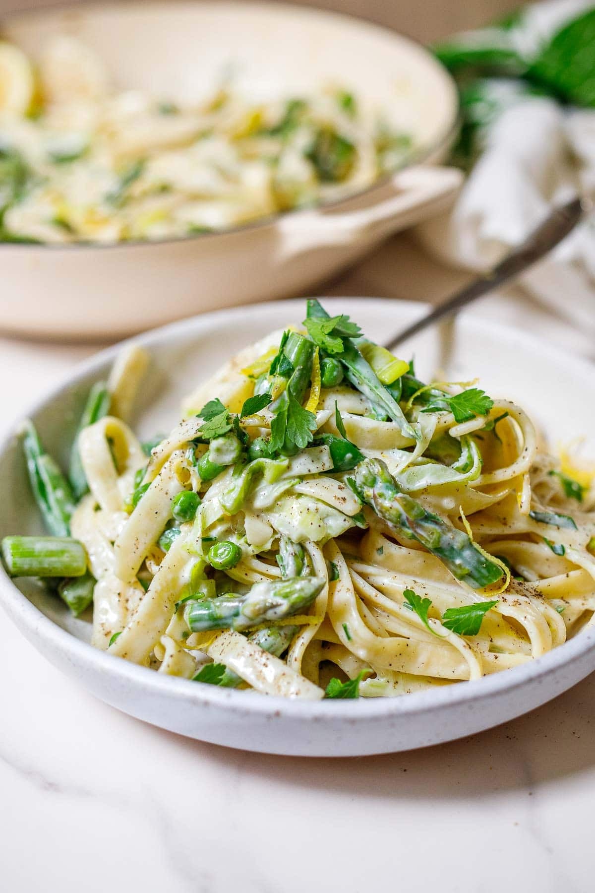 This light and creamy pasta primavera makes the perfect spring dinner! Tender pasta and spring vegetables are kissed with a light cream sauce infused with lemon and herbs. 