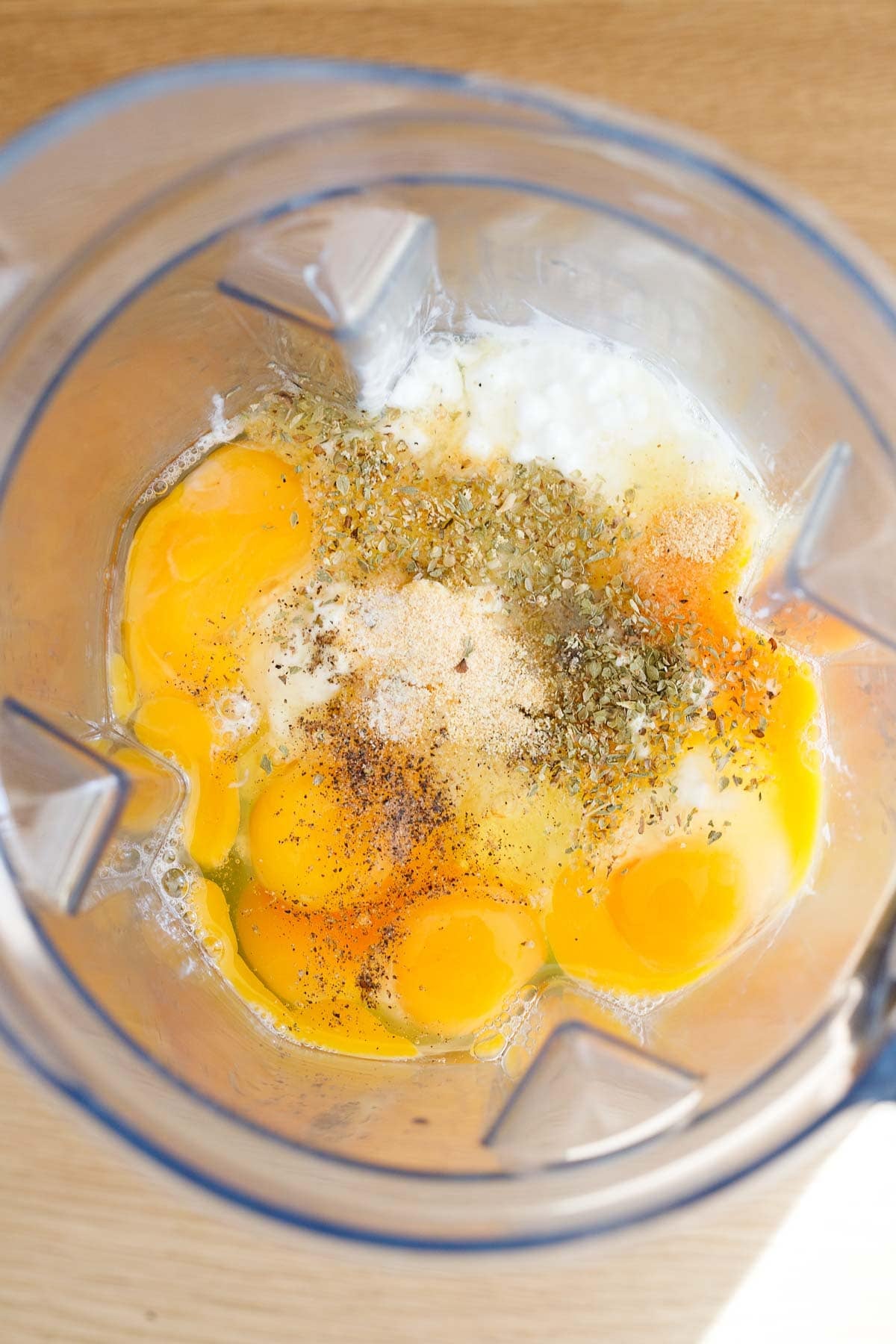 top view of blender with eggs, cottage cheese, and spices. 