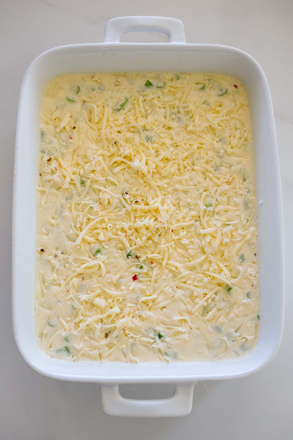 breakfast casserole before going into the oven, with grated pepper jack cheese spread over the top. 