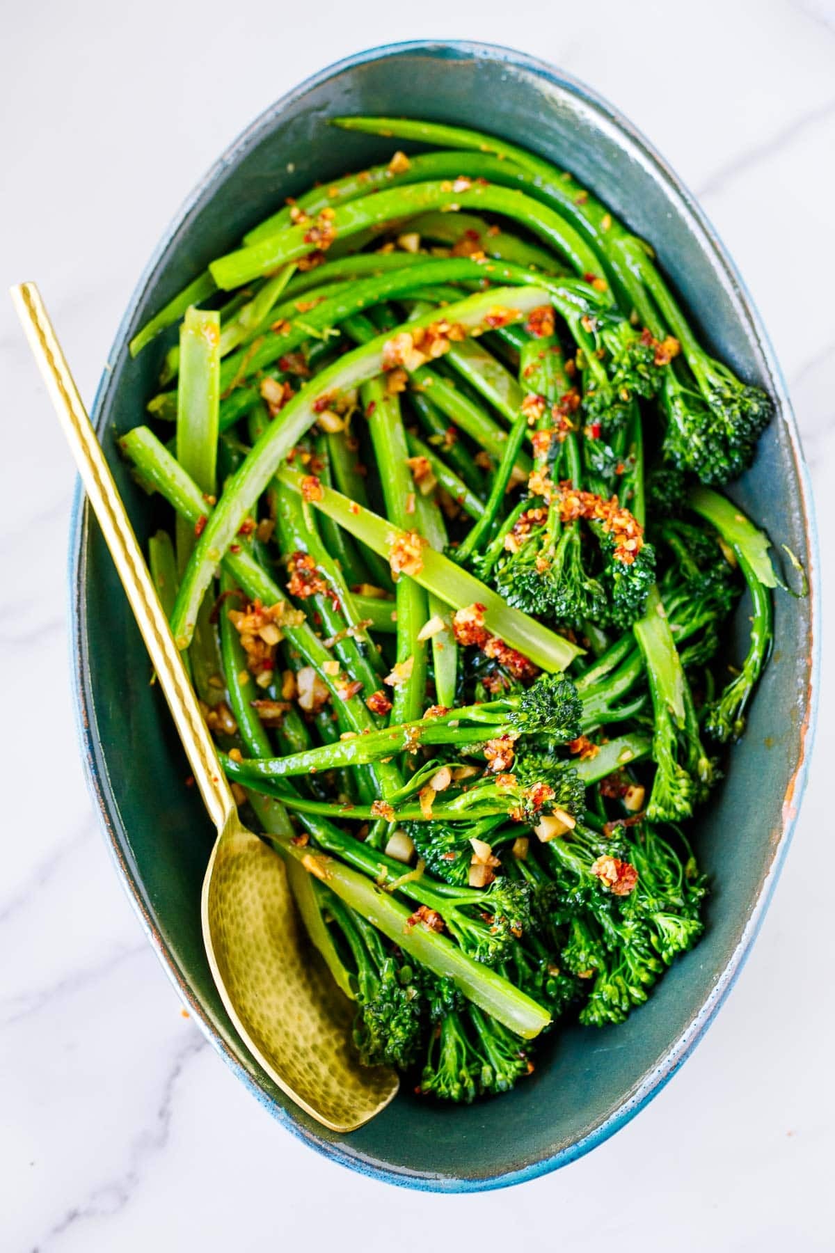 tender-crisp broccolini with chili crisp in serving dish with spoon. 