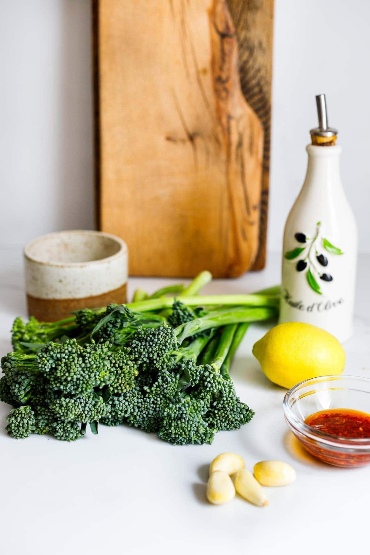 ingredients for broccolini - olive oil, broccolini, lemon, chili crisp, garlic cloves. 