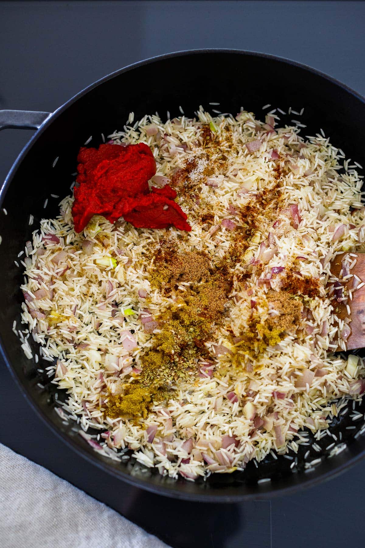 tomato paste and spices added to skillet with toasted rice.