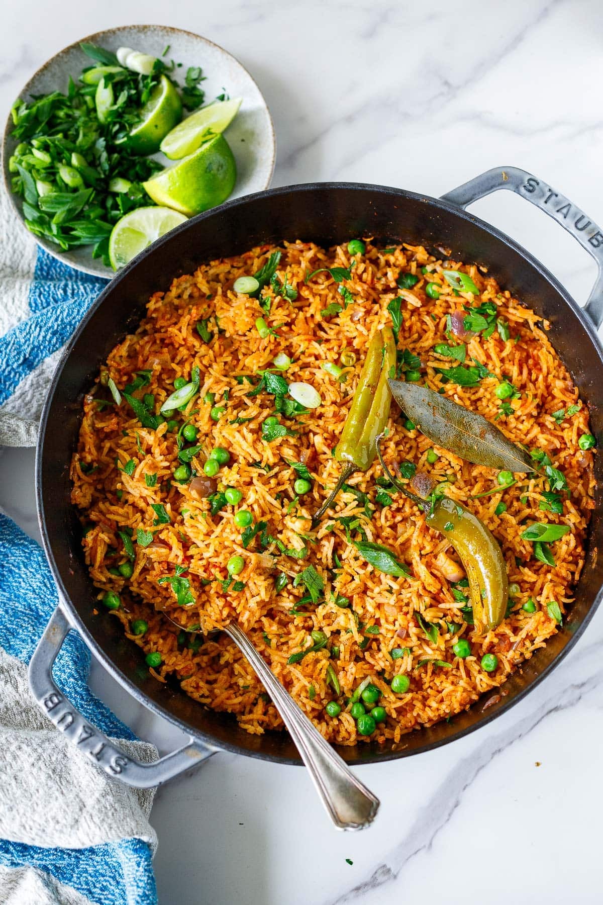 Dutch oven with Spanish rice topped with cilantro, green onions, serrano chilies, and bay leaf.