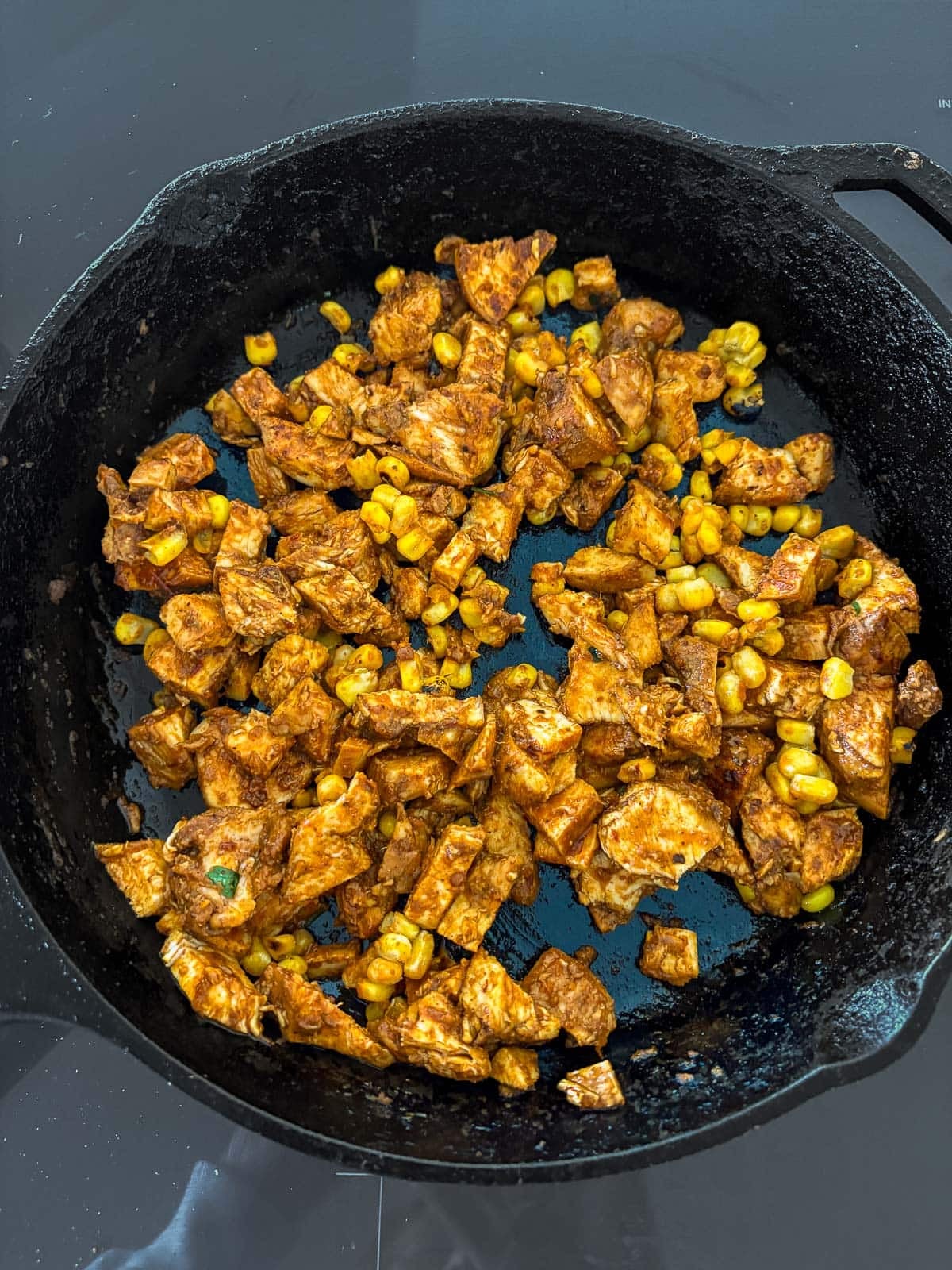 reheating chipotle chicken with a handful of corn in a skillet. 