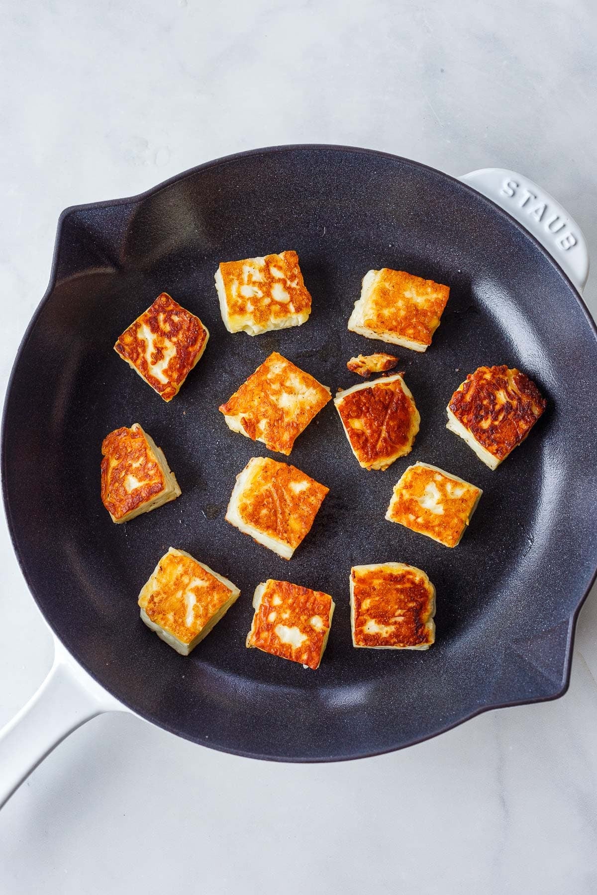 halloumi squares searing in a skillet.