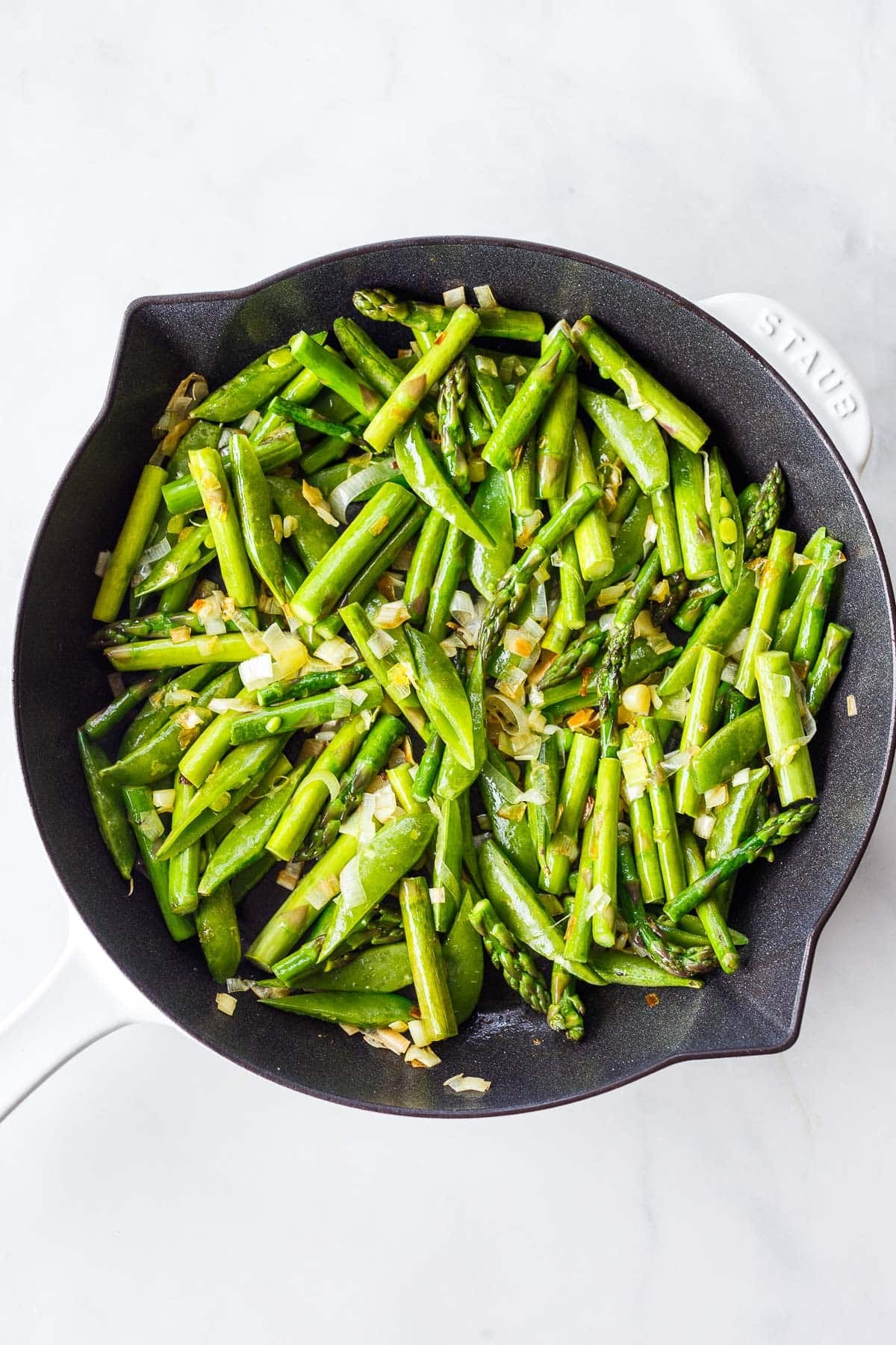 asparagus and snap peas in a skillet with sautéed leeks.