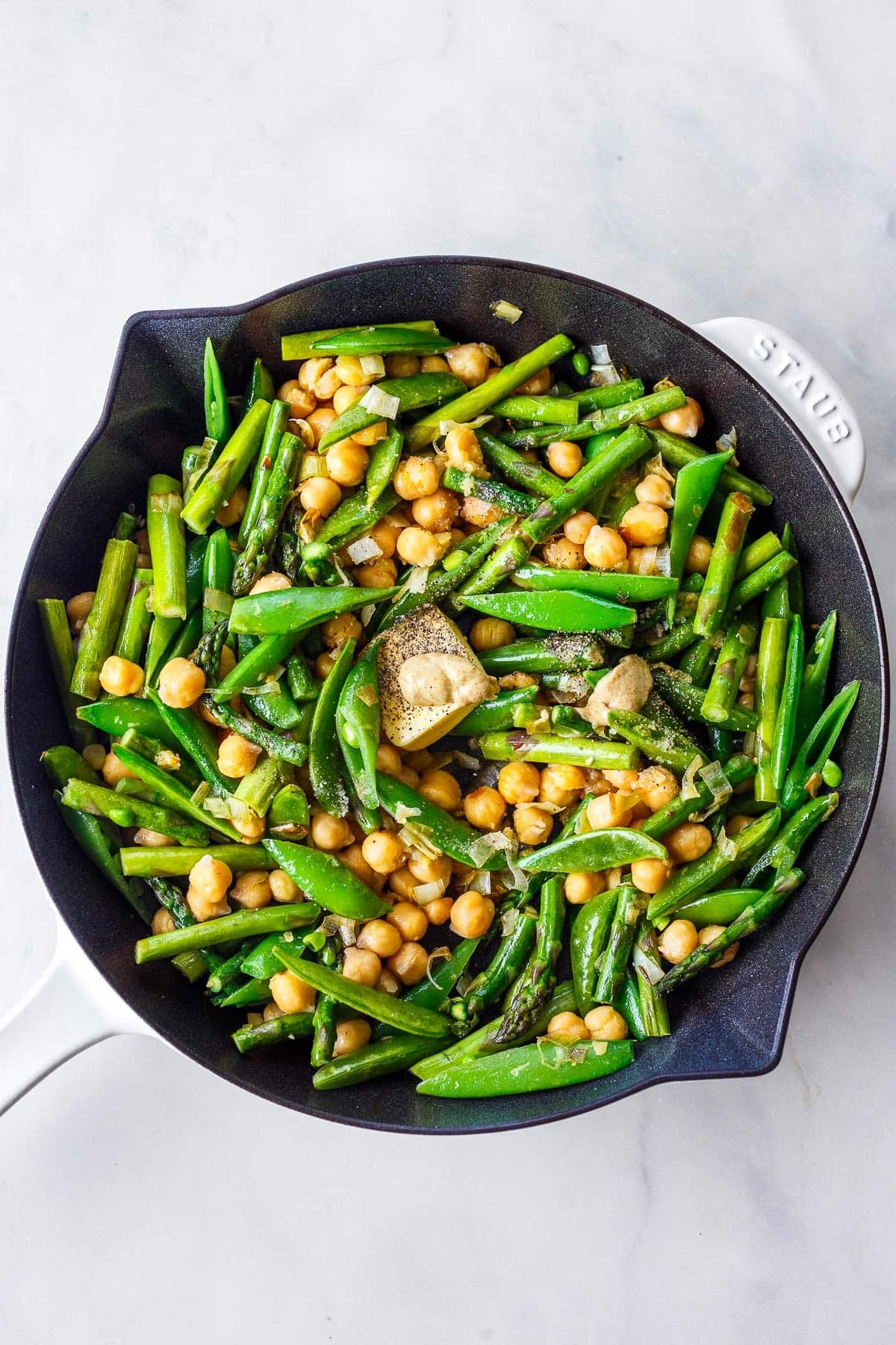 skillet with sautéed spring vegetables with pat of butter, salt and pepper, and Dijon mustard.