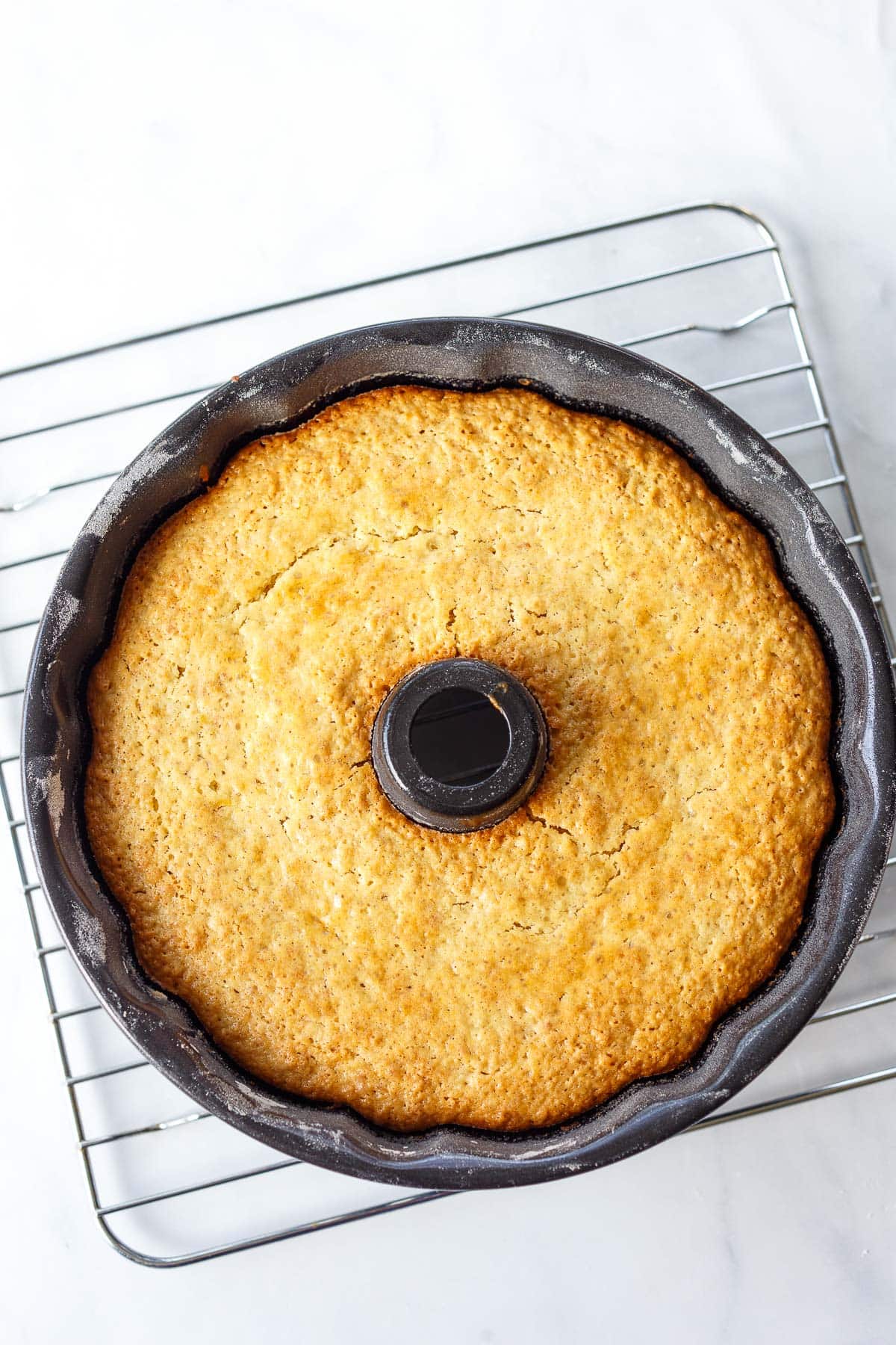 baked vegan lemon bundt cake cooling in bundt pan on wire rack.