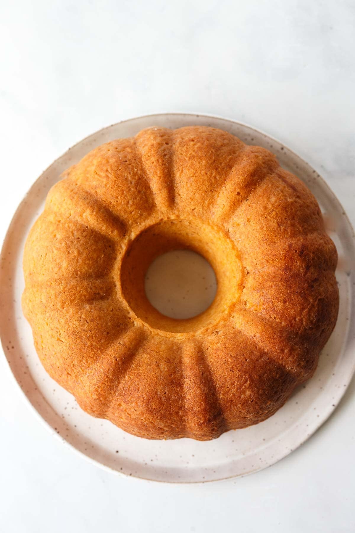baked vegan lemon bundt cake on cake plate.