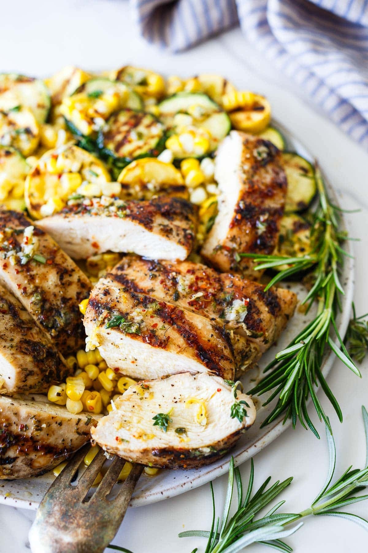 Mediterranean grilled chicken, sliced, with lemon sauce, fresh herbs, grilled corn, and sliced grilled zucchini.