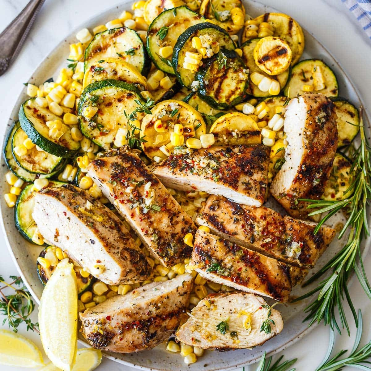 Mediterranean Grilled Chicken is an easy, flavor-packed summer dinner made with juicy herb-marinated chicken breasts, charred zucchini, and sweet grilled corn. Bright lemon, garlic, and fresh herbs infuse every bite! Gluten-free.
