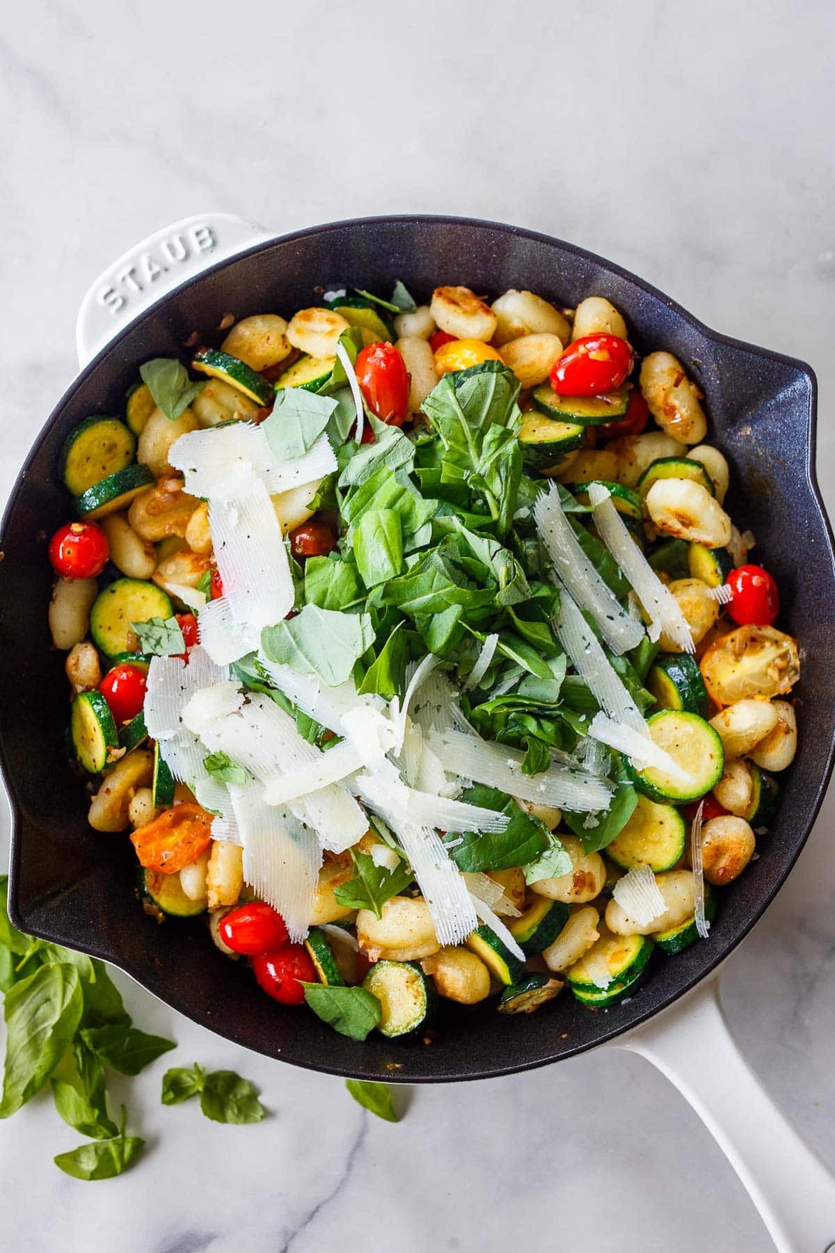pan-fried gnocchi in a skillet with sautéed zucchini and cherry tomatoes, fresh basil, and shaved pecorino.