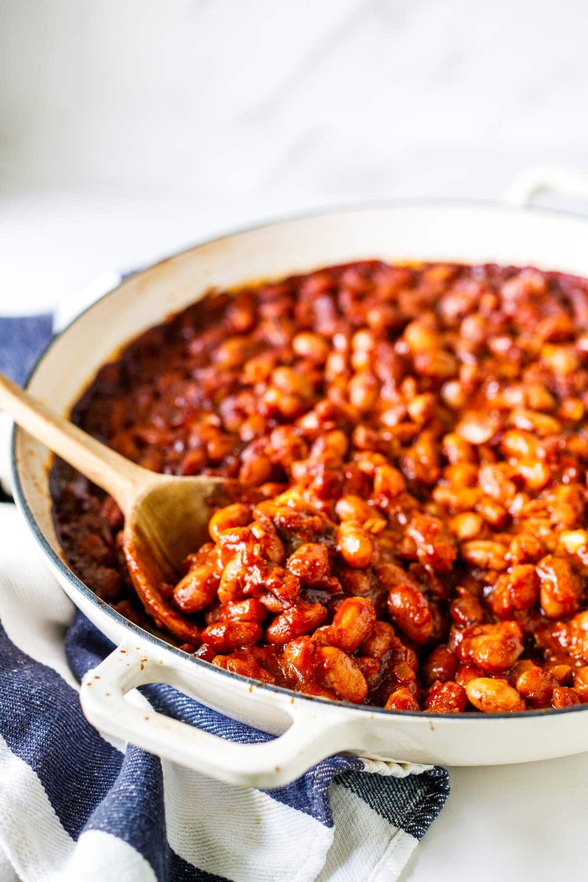 wood spoons scooping up baked beans bbq style in a braiser.