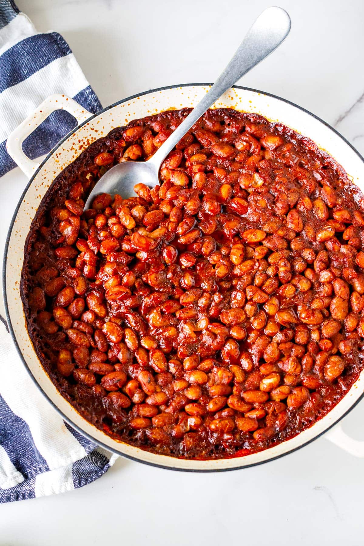 baked beans in a braiser with a silver spoon.