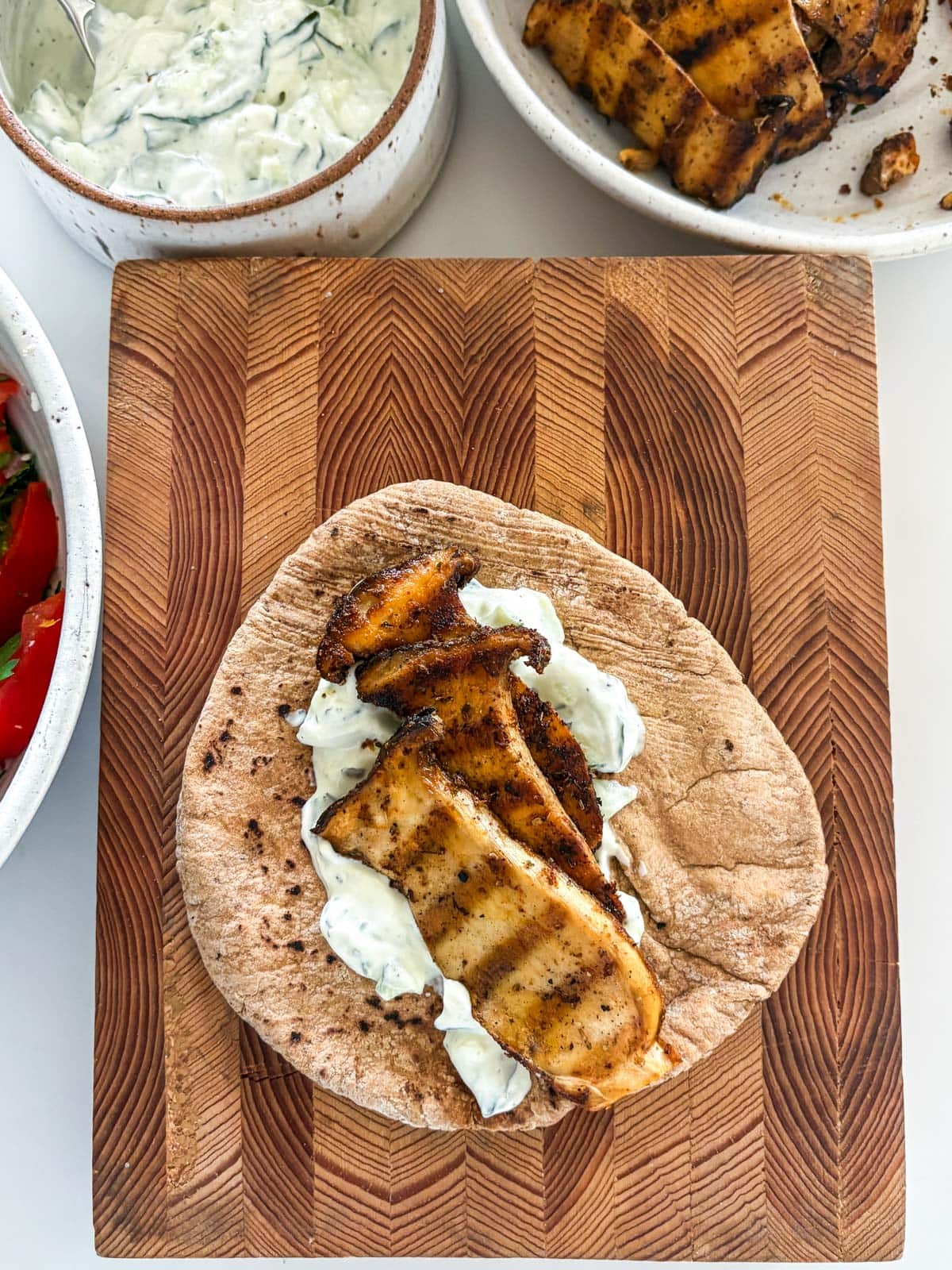 assembling Greek souvlaki pita with tzatziki and sliced and grilled king oyster mushrooms.