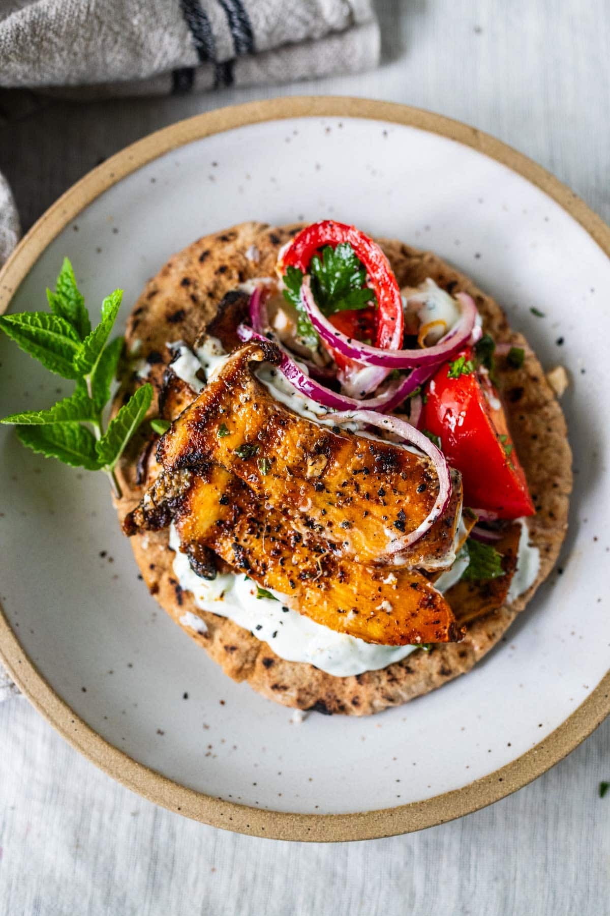 pita bread topped with tzatziki, tomato feta and red onion salad, parsley, and grilled king oyster mushroom with souvlaki marinade.