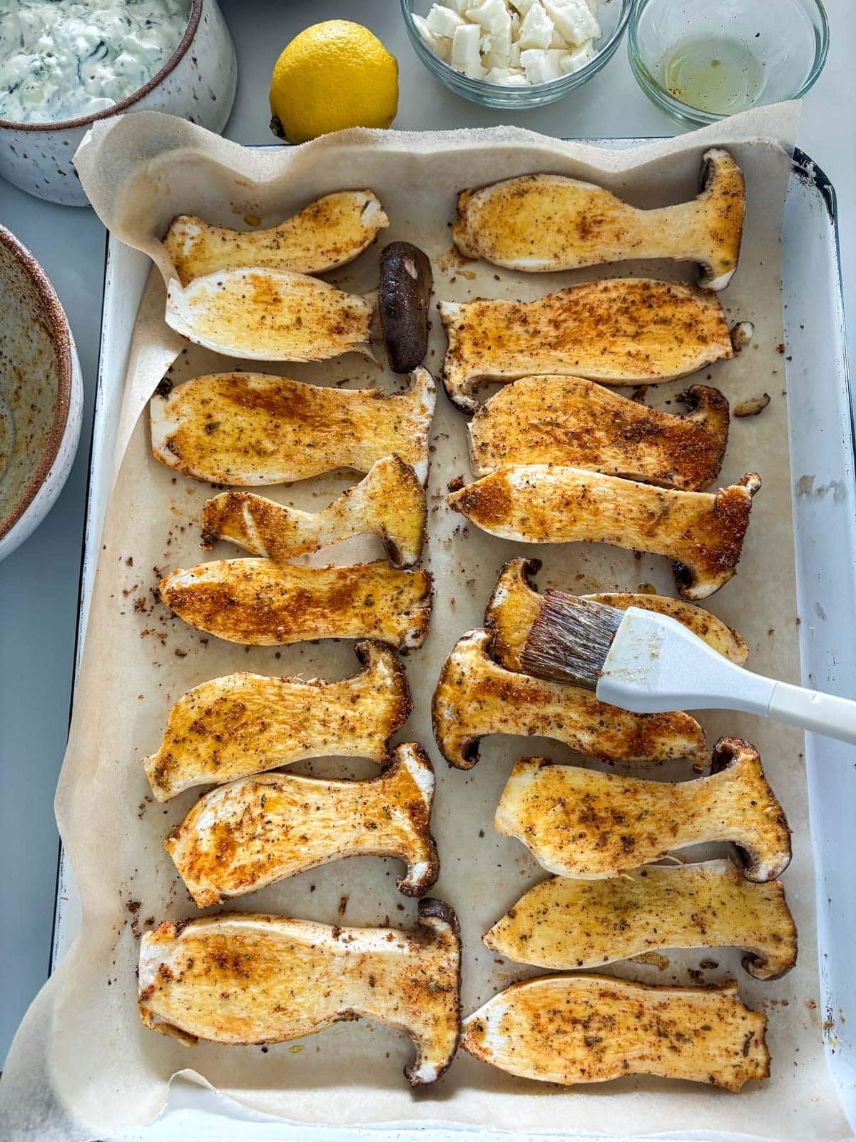 brushing souvlaki marinade on sliced king oyster mushrooms.