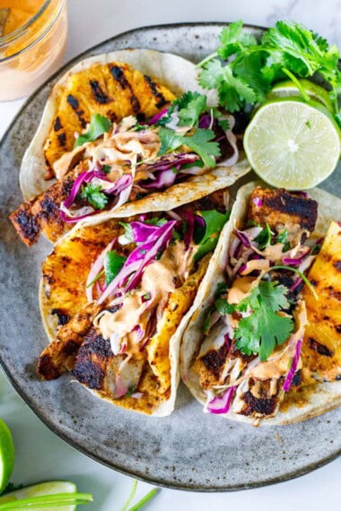 These mahi mahi tacos are fresh, flavorful, and easy to make with smoky spiced fish, grilled pineapple, crunchy cabbage slaw, and a creamy chipotle sauce.