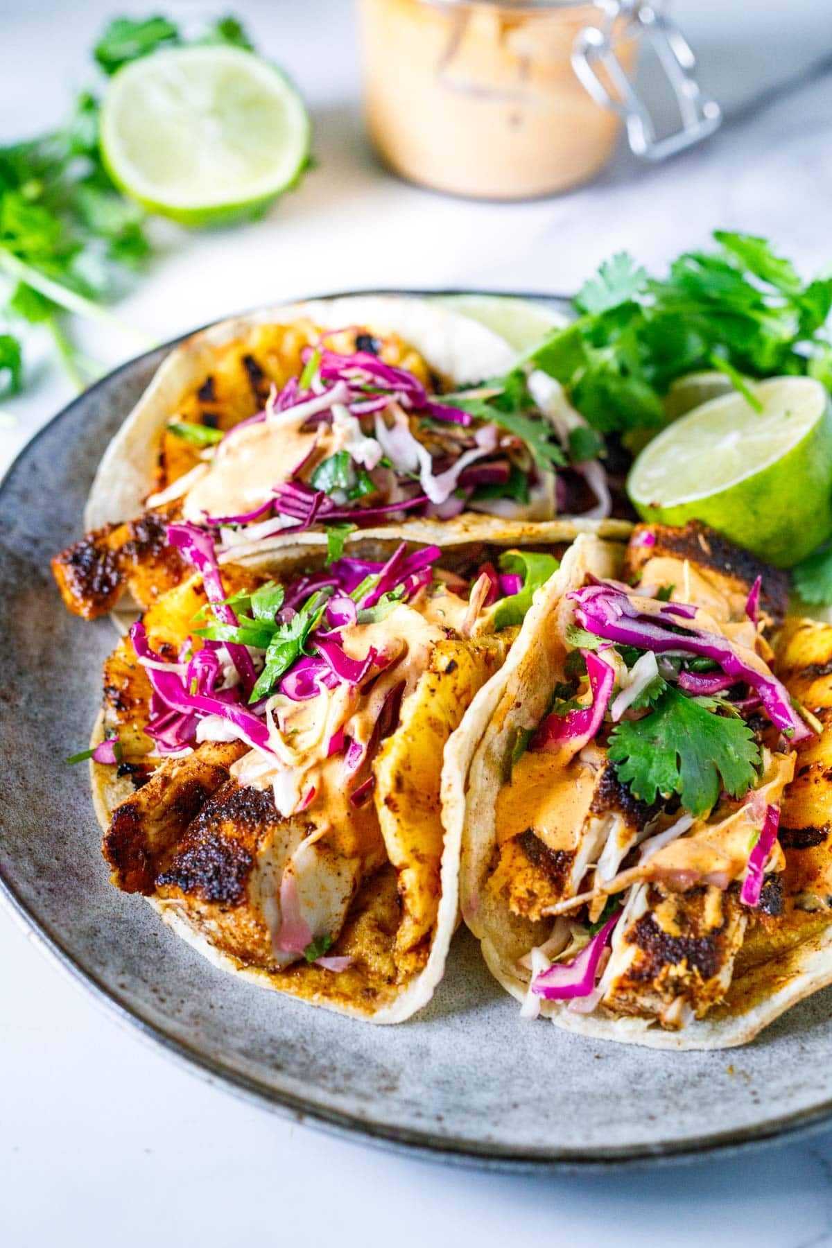 plate of mahi mahi tacos with grilled mahi mahi and pineapple, slaw, cilantro, and lime.