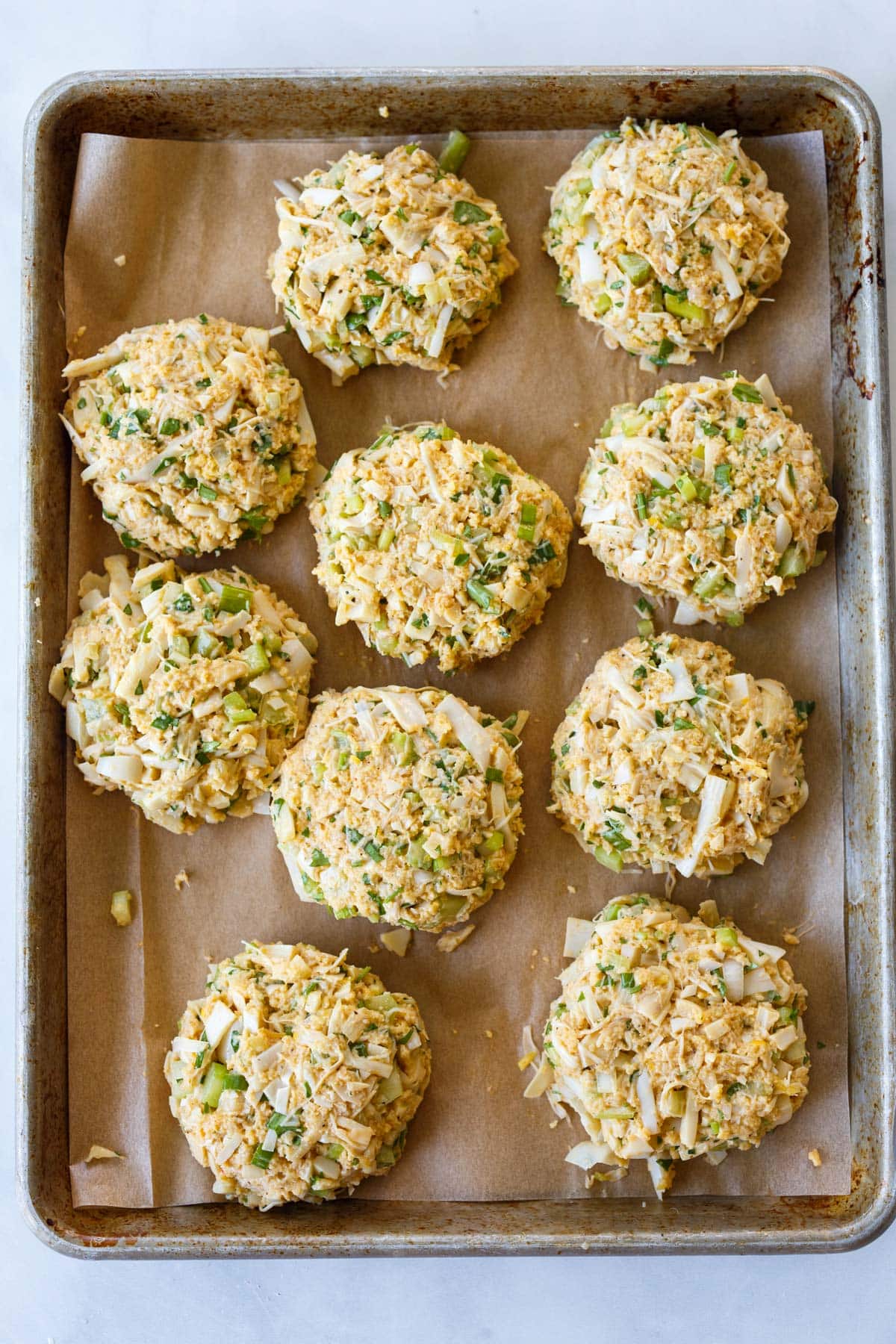 parchment-lined baking sheet with vegetarian crab cake patties formed.