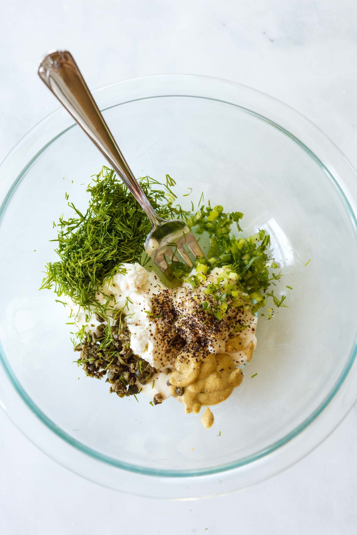 fork mixing lemon dill sauce in a bowl.