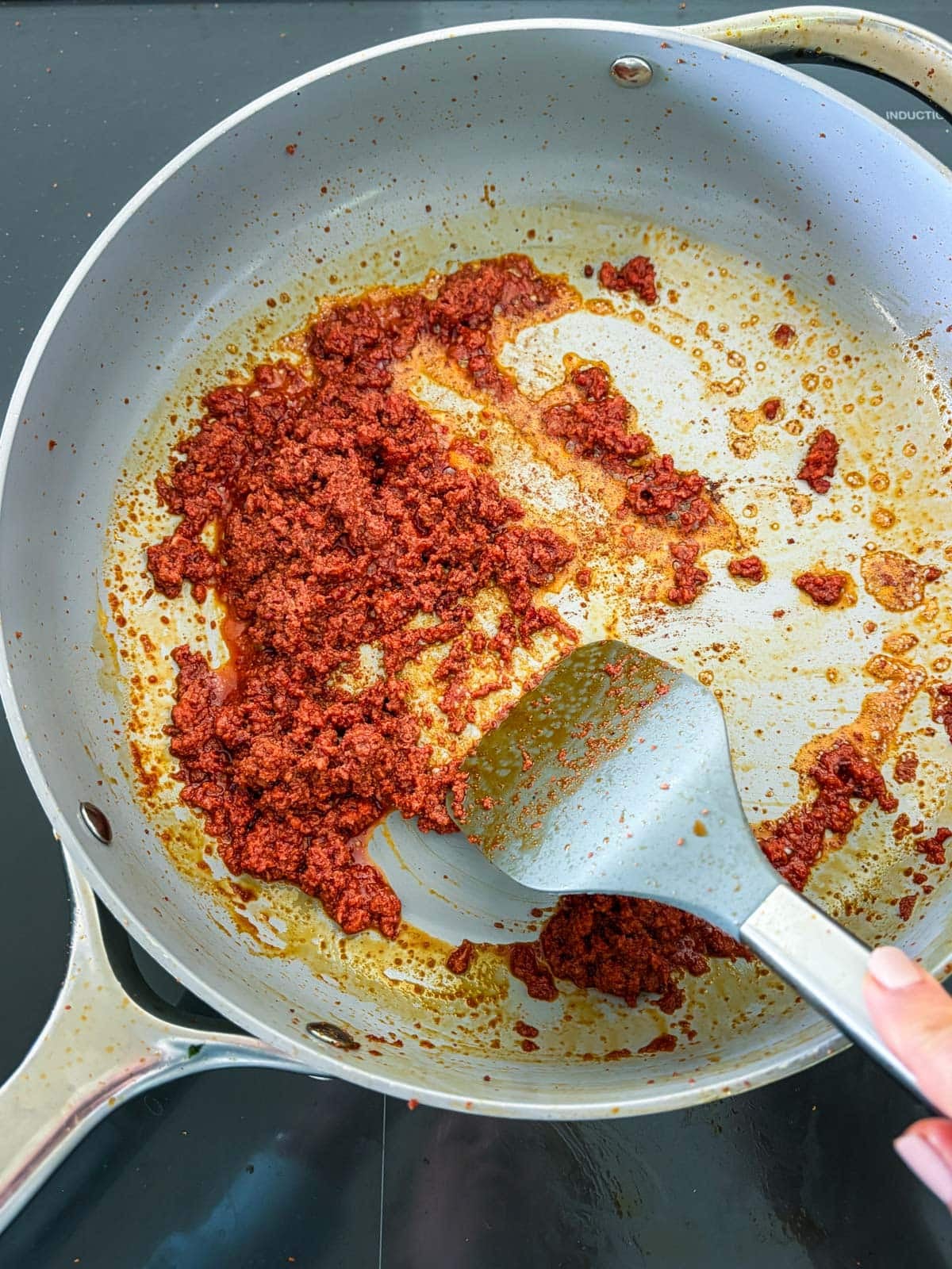 sautéing chorizo in a non-stick skillet with a spatula.