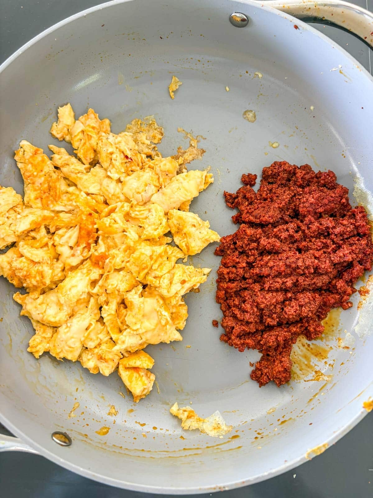 non-stick skillet with scrambled eggs on one side and chorizo on the other.