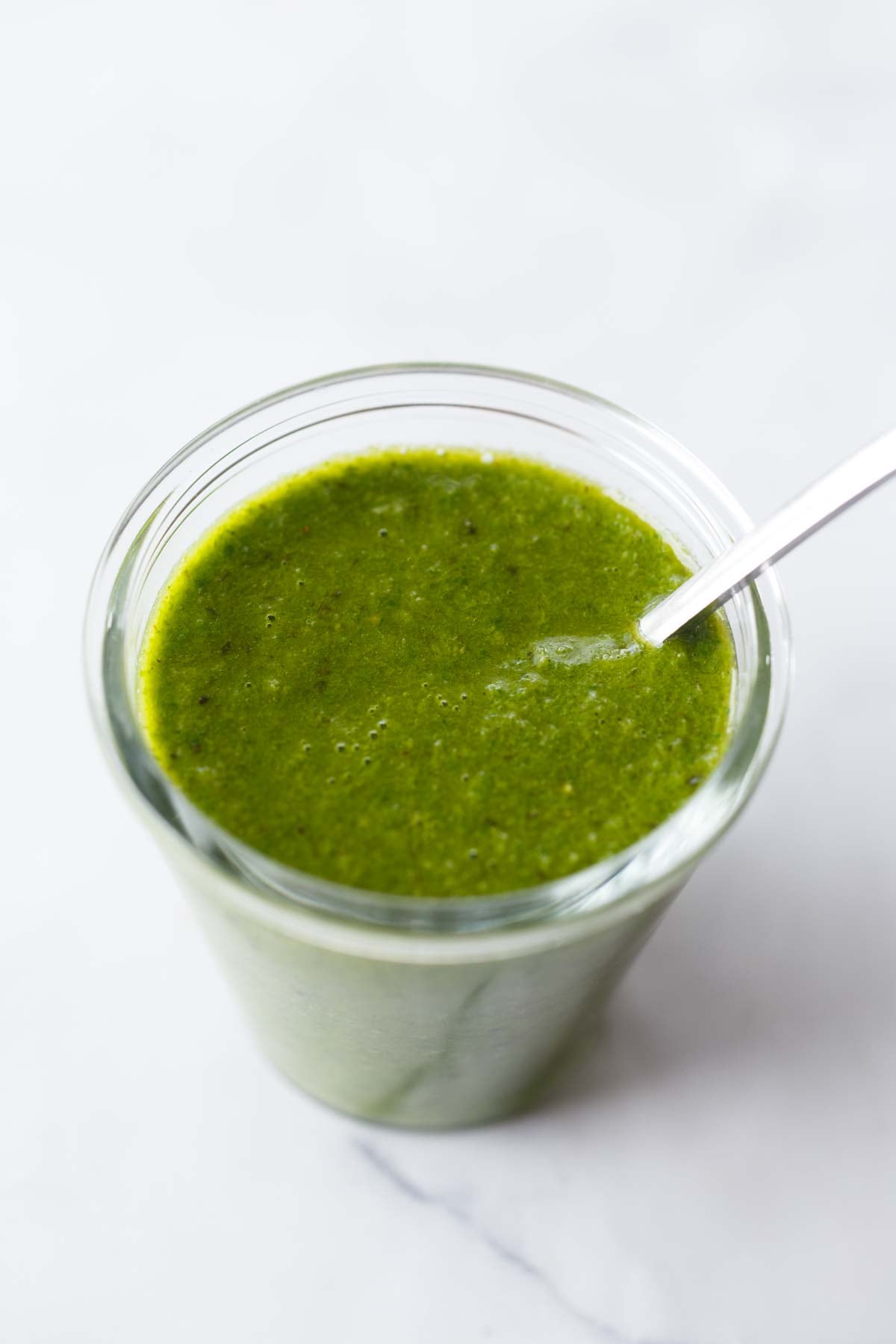 glass jar of basil vinaigrette with spoon.
