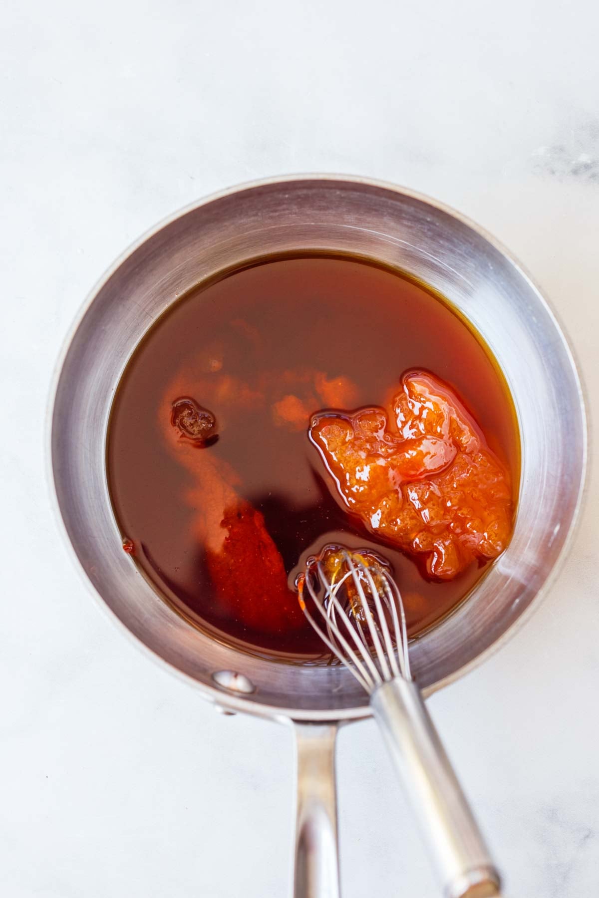saucepan with glaze for Korean meatballs and a whisk.