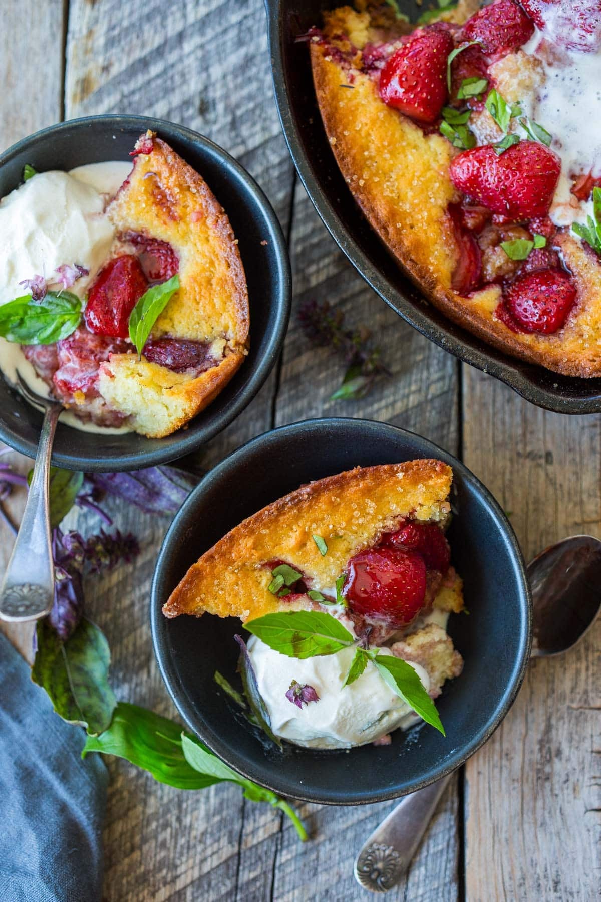 two bowls of strawberry cobbler with vanilla ice cream and fresh basil.
