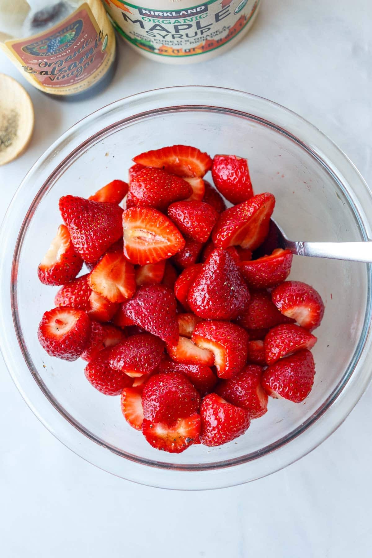 bowl of halved strawberries in a glass mixing bowl.