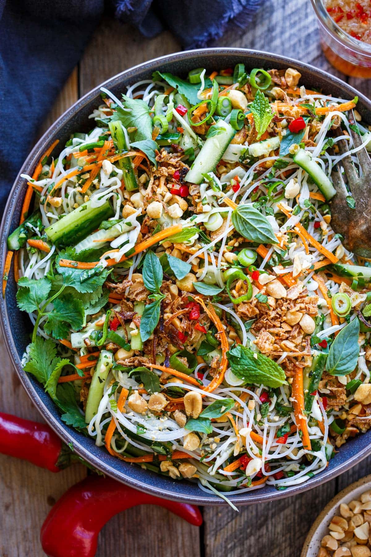 Vietnamese vermicelli salad in a bowl with peanuts, crispy shallots, red chilies, carrots, cucumbers, cilantro, mint, and basil.