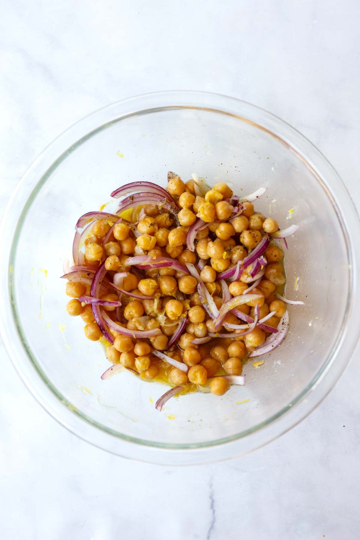 chickpeas and thinly sliced red onion in a glass mixing bowl.