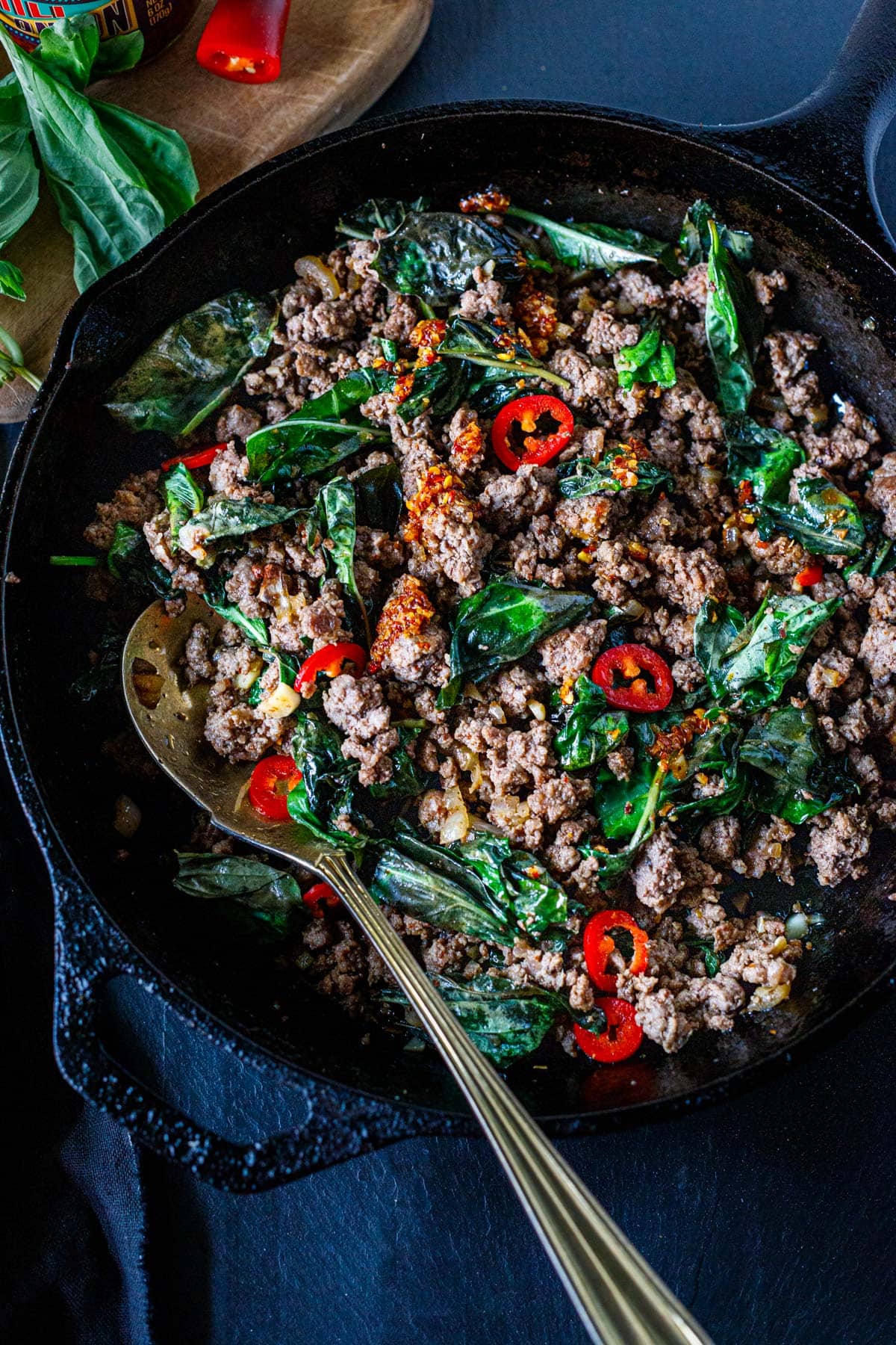 basil beef with red chilies and chili crisp in a cast iron skillet.