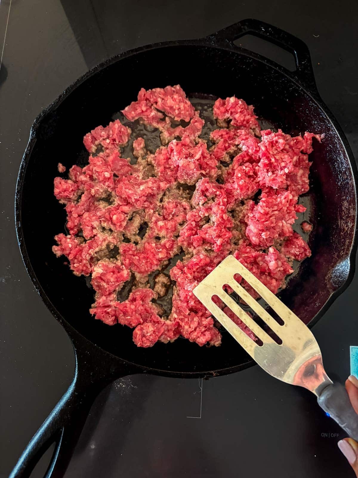 brown ground beef in a cast iron skillet with a metal spatula. 