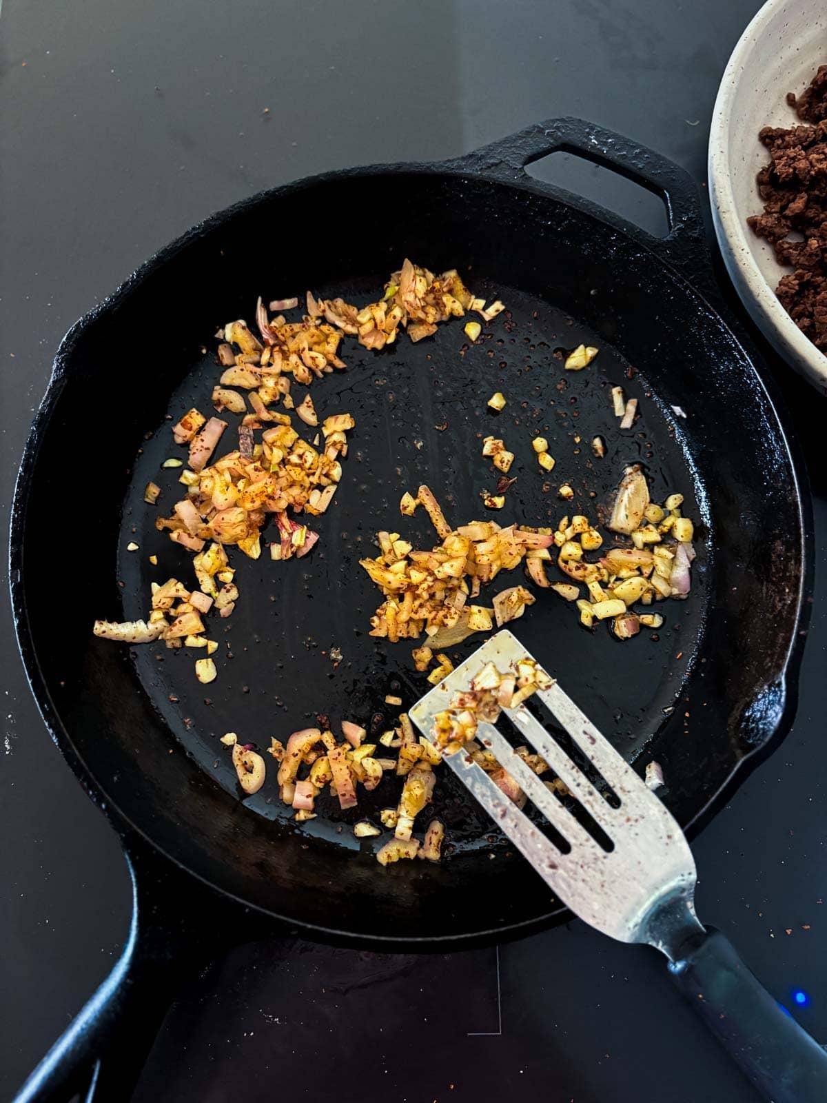 sautéing garlic and shallots in a cast iron skillet with a metal spatula. 