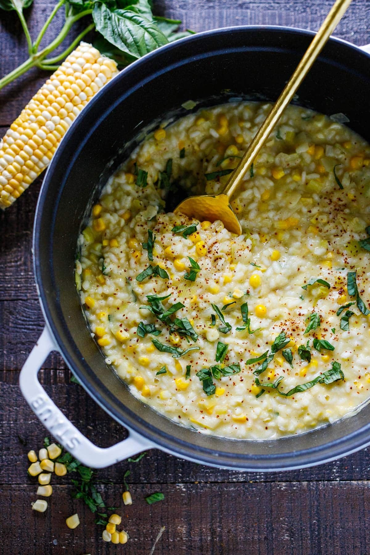 Dutch oven with corn risotto toped with chili flakes and fresh basil.