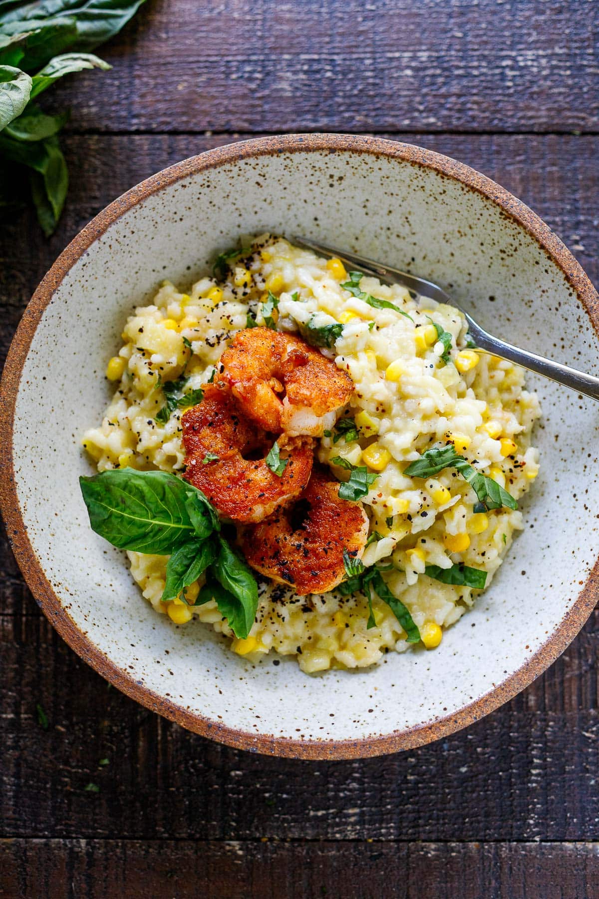 smoky seared shrimp on top of a bowl of sweet corn risotto with fresh basil.