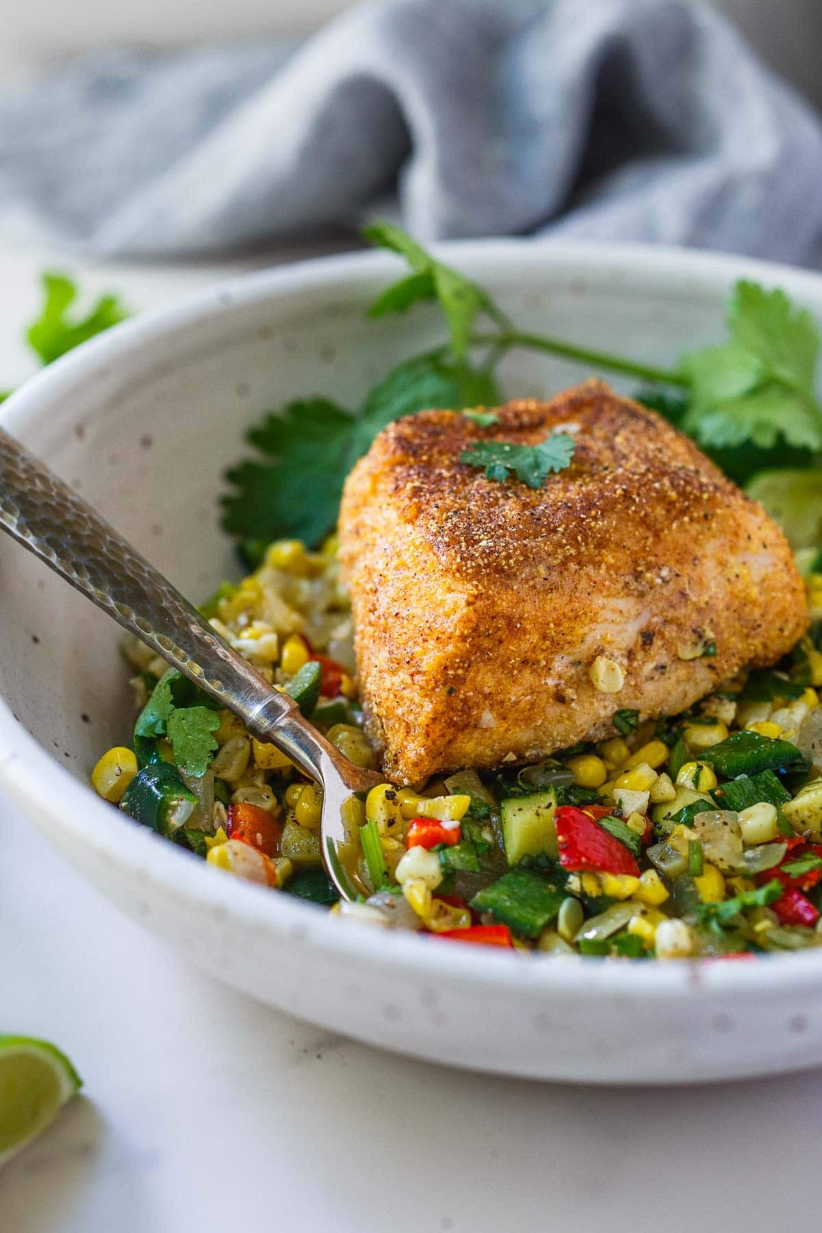 cornmeal-crusted halibut on a bowl of succotash, topped with fresh cilantro.