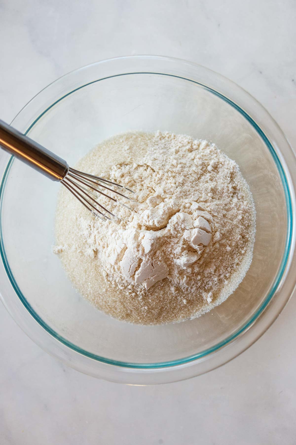 whisking flour and sugar together in a glass bowl.
