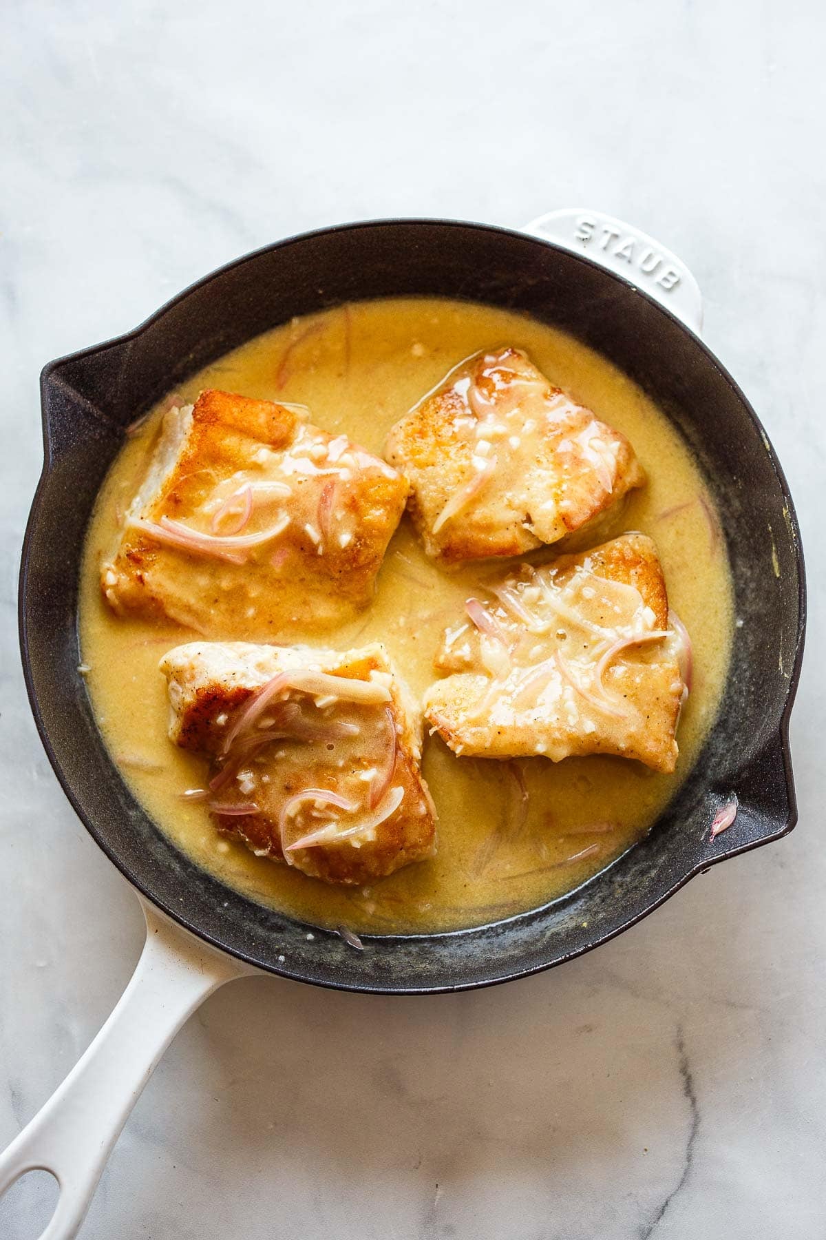 four seared cod fillets in lemon butter sauce.