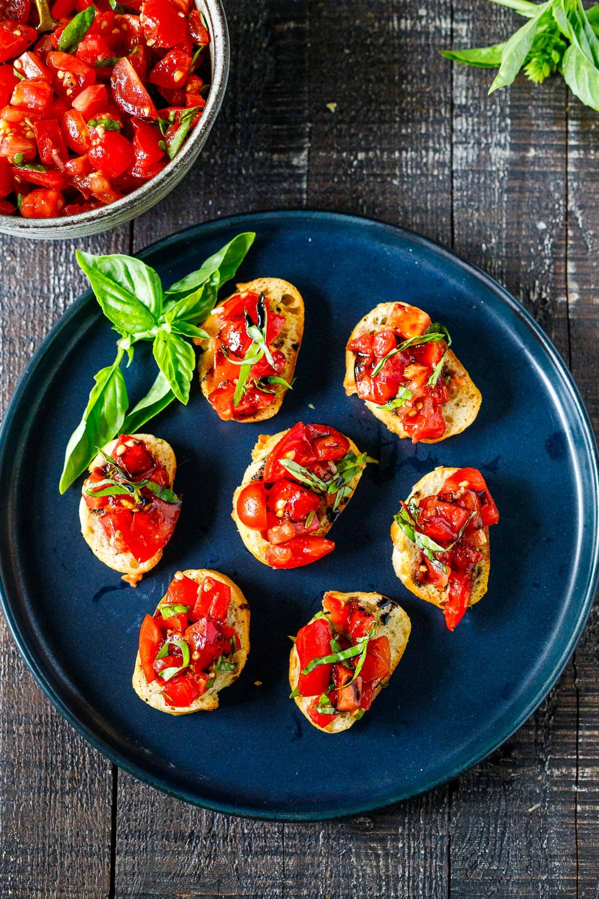 tomato bruschetta on a small platter with a drizzle of balsamic glaze